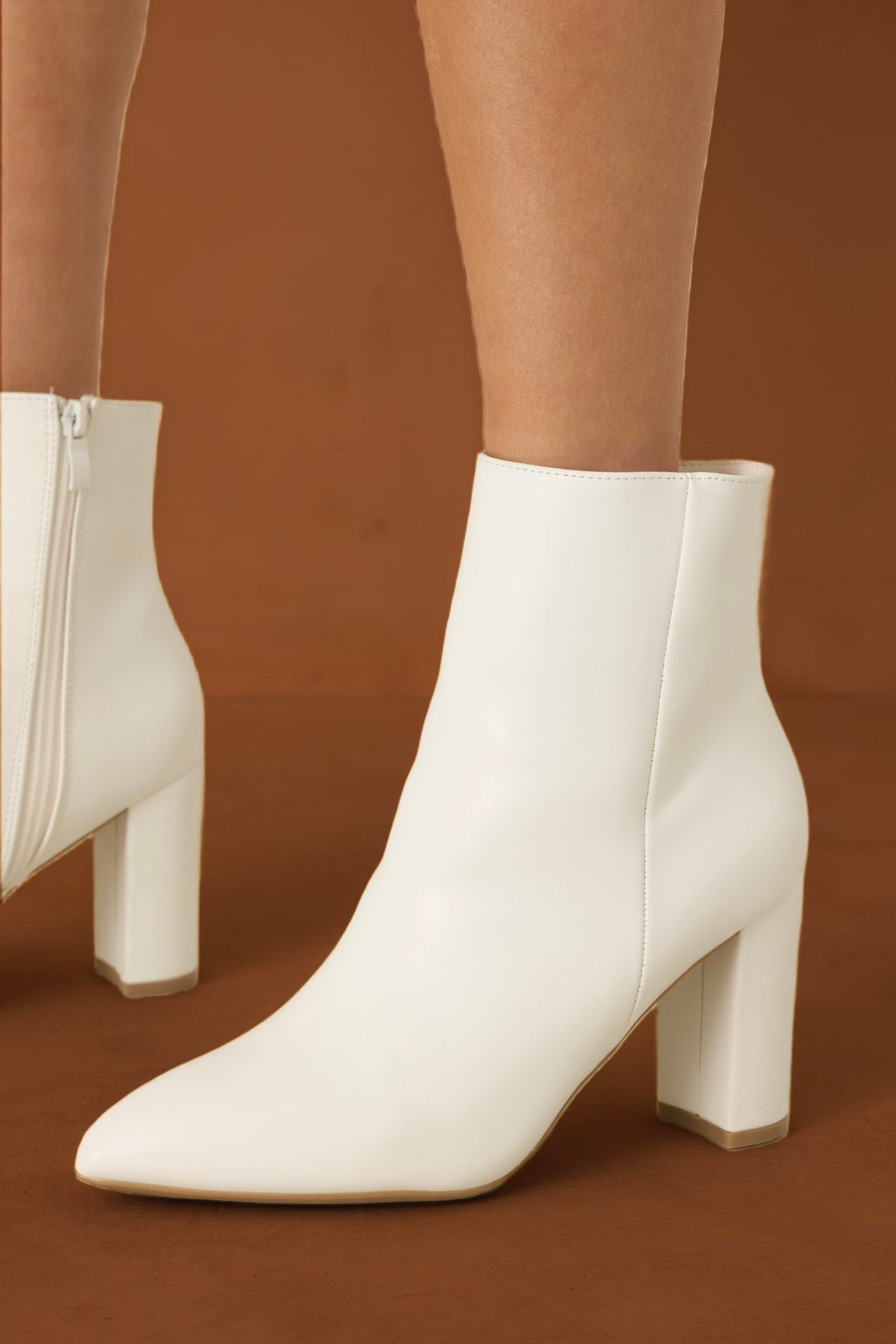 White booties against a burnt orange backdrop. 