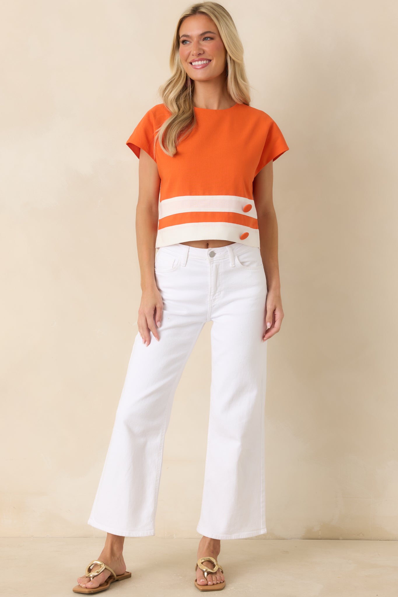 Retro-inspired top showcasing a boxy silhouette, covered button details, and wide white stripe accents across the hemline.