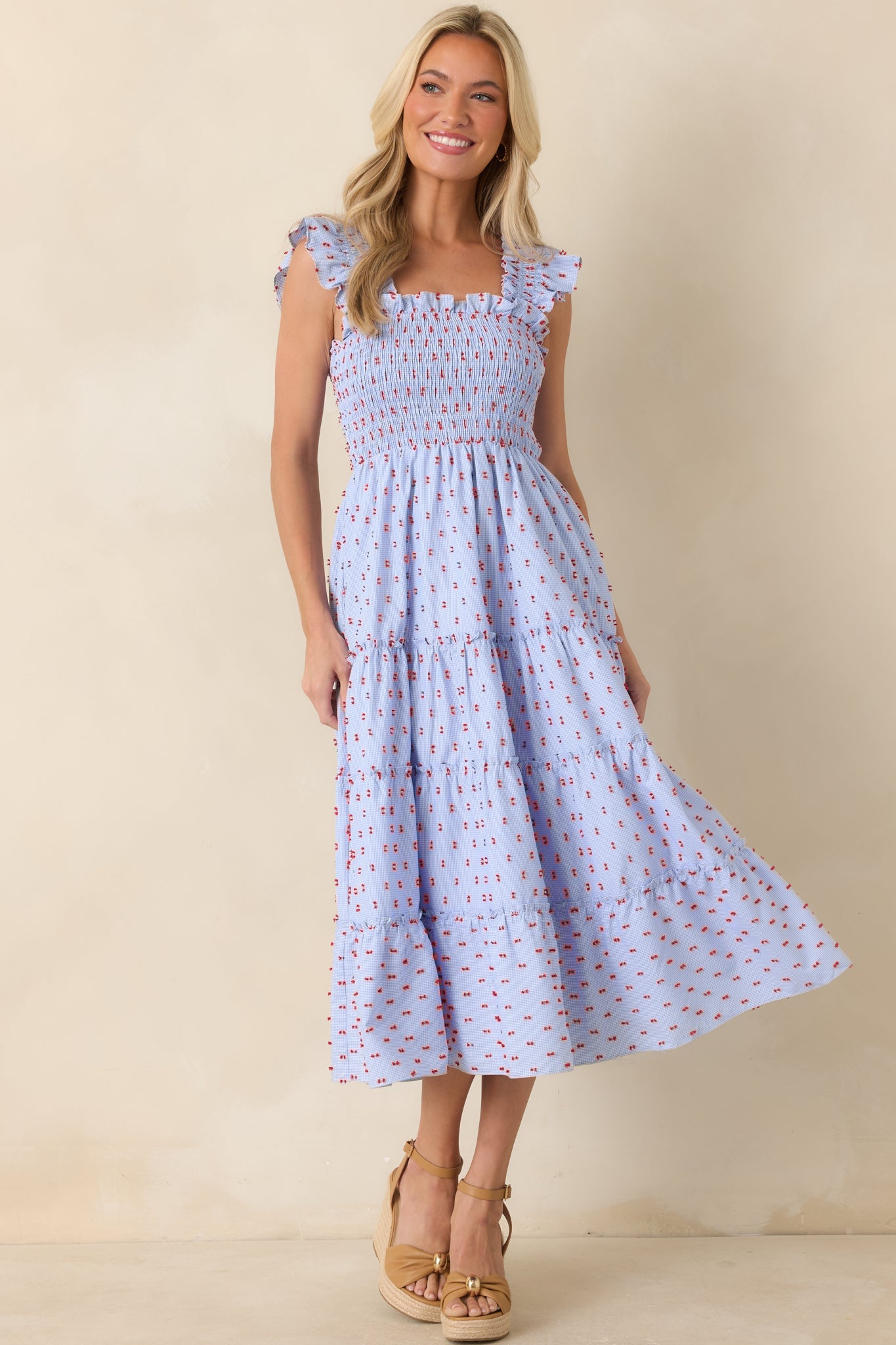 Blue gingham midi dress featuring red tufted embroidery, a fully smocked bodice, and a flowing tiered skirt.