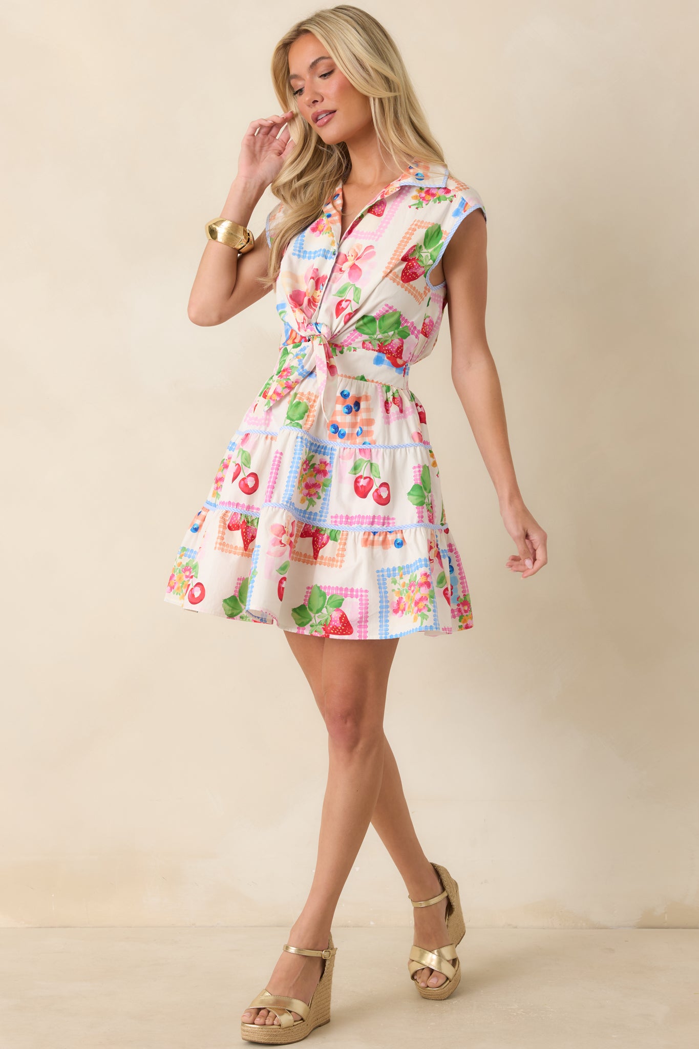 Multi fruit and floral mini dress featuring cap sleeves, a fitted waist tie, and a relaxed, playful silhouette.
