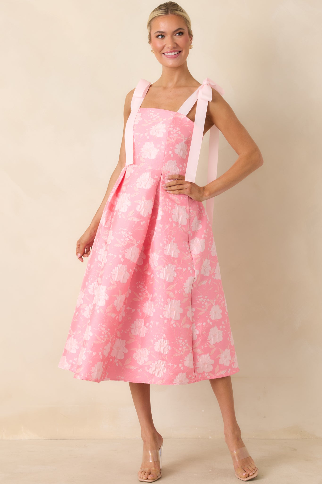 Midi dress with square neckline, bow-tie shoulder straps, and a softly structured pleated skirt.