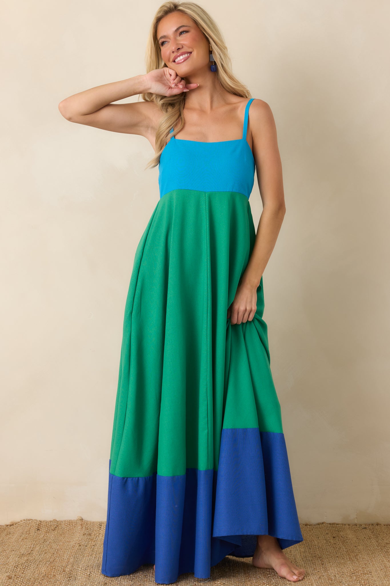 Full-length dress featuring a structured square neckline, flowing skirt movement, and playful contrast hem detailing.