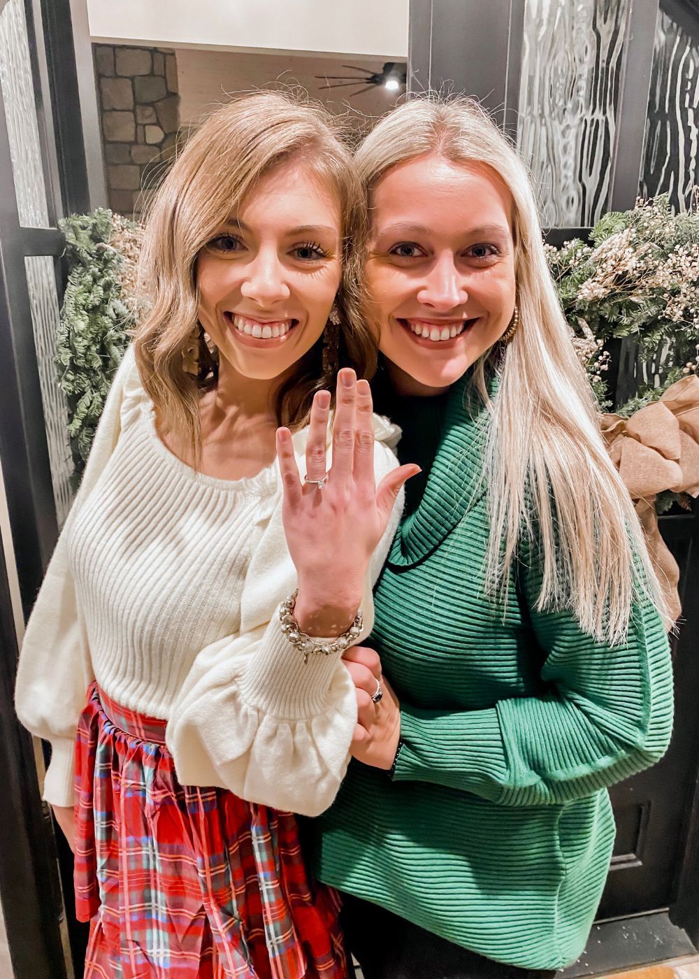 Two women posing together, one wearing a ring on her finger.