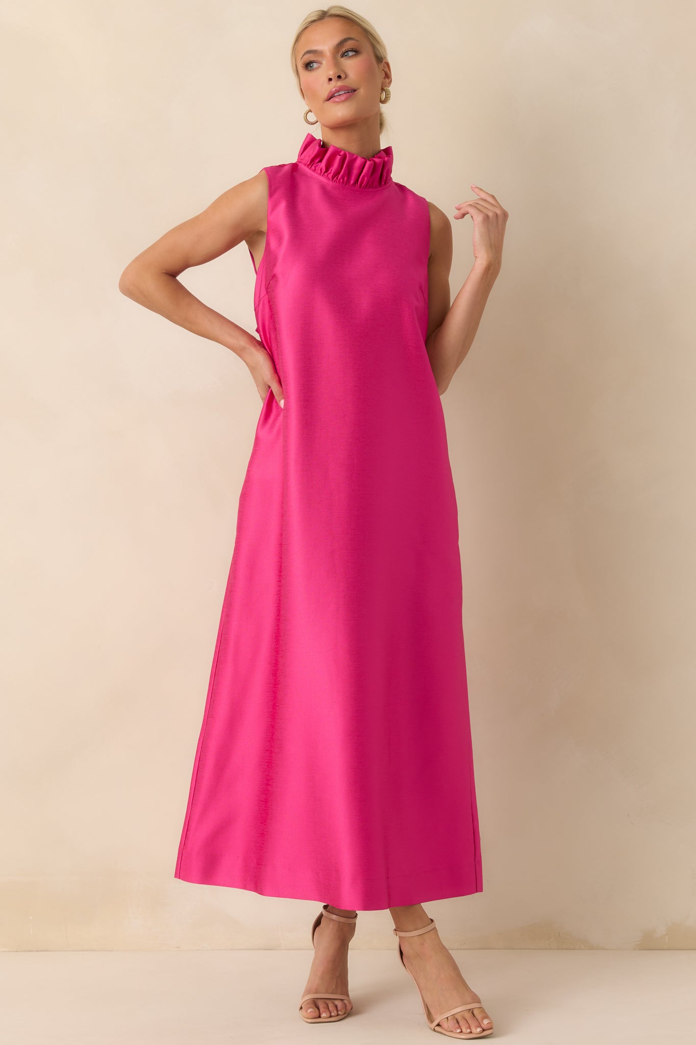 Hot pink maxi dress with a ruffle mock neckline, sleeveless silhouette, and flowing straight drape from the shoulders.