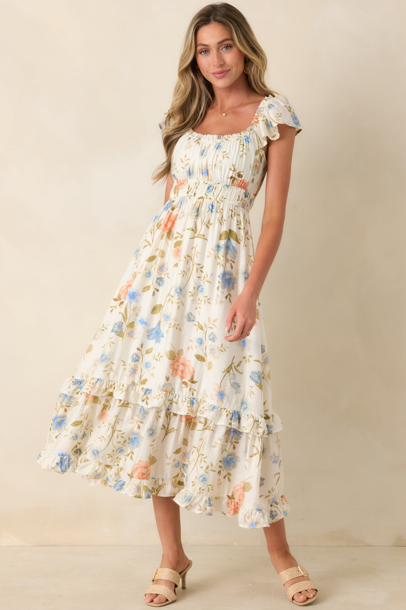 Ivory multi floral midi dress featuring flutter sleeves, scoop neckline, and a ruffled tiered skirt with a soft, lightweight drape.