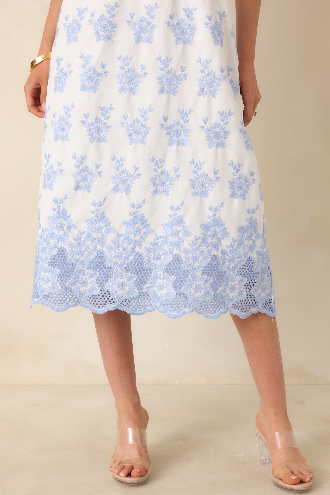 Scalloped hem with intricate blue floral embroidery on white fabric