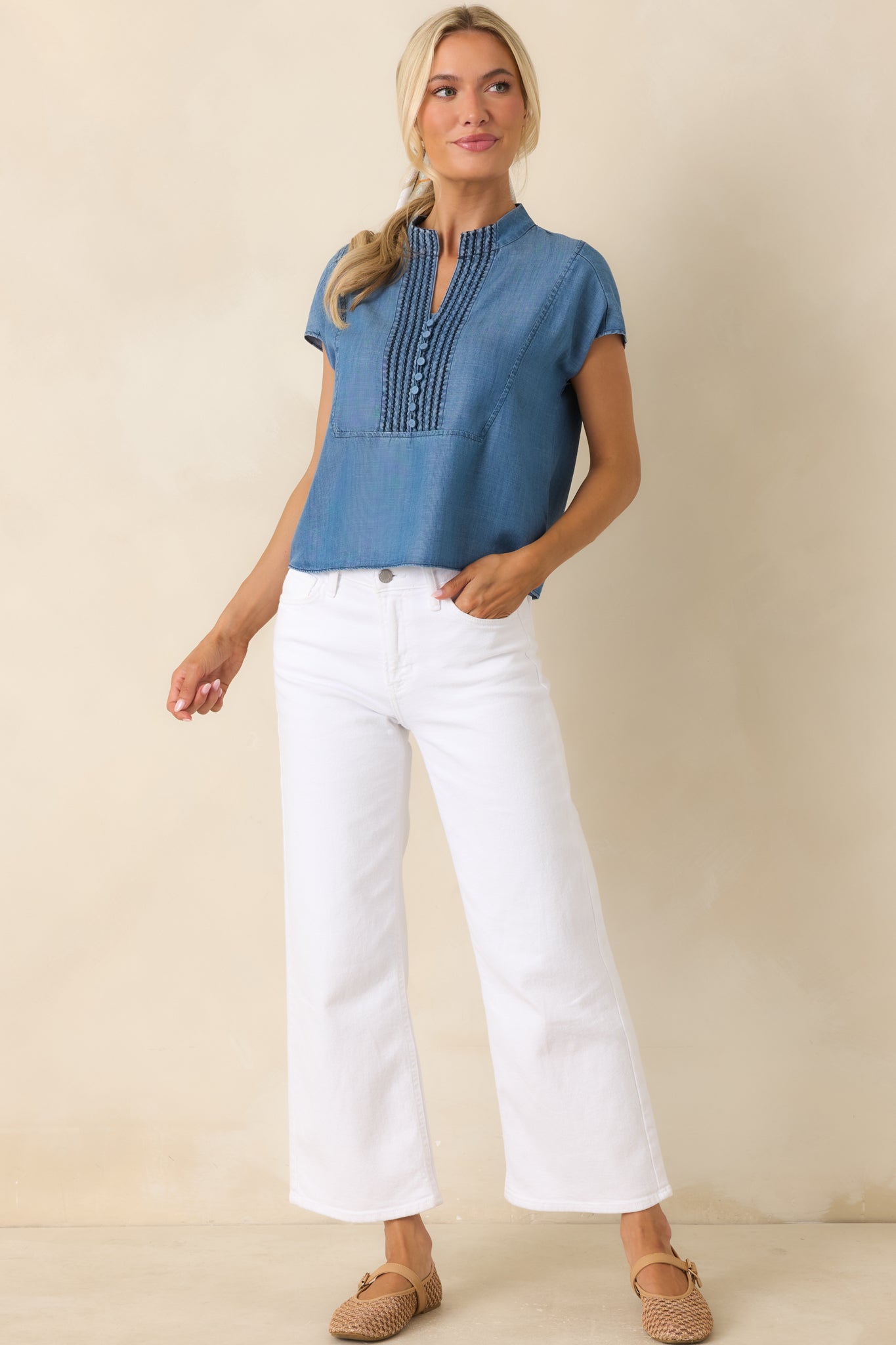 Blue lightweight top featuring a split neckline, embroidered pintuck front detailing, and a relaxed silhouette.