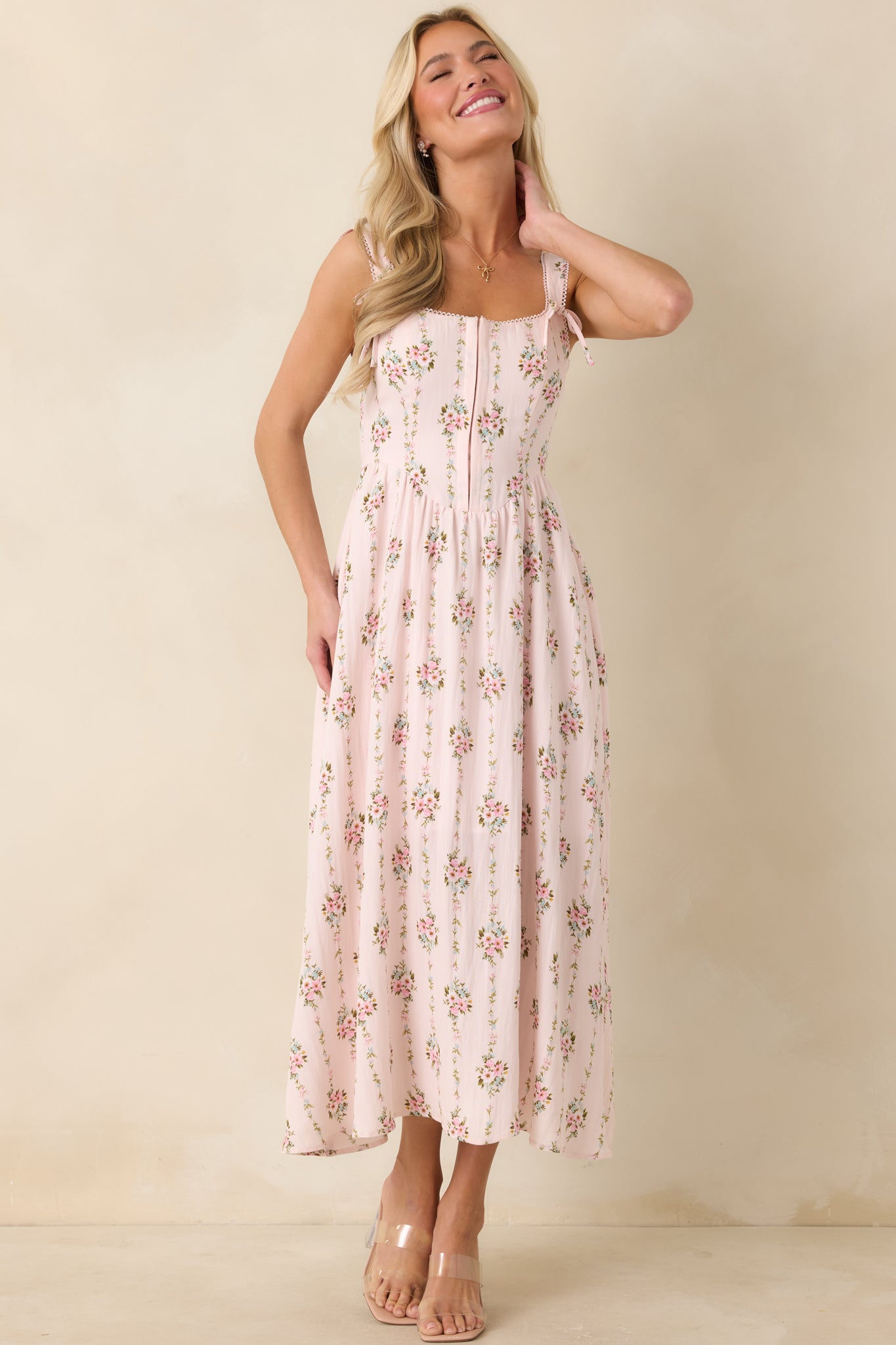 Floral midi dress in light pink tones featuring front hook and eye detail and delicate strap ties.