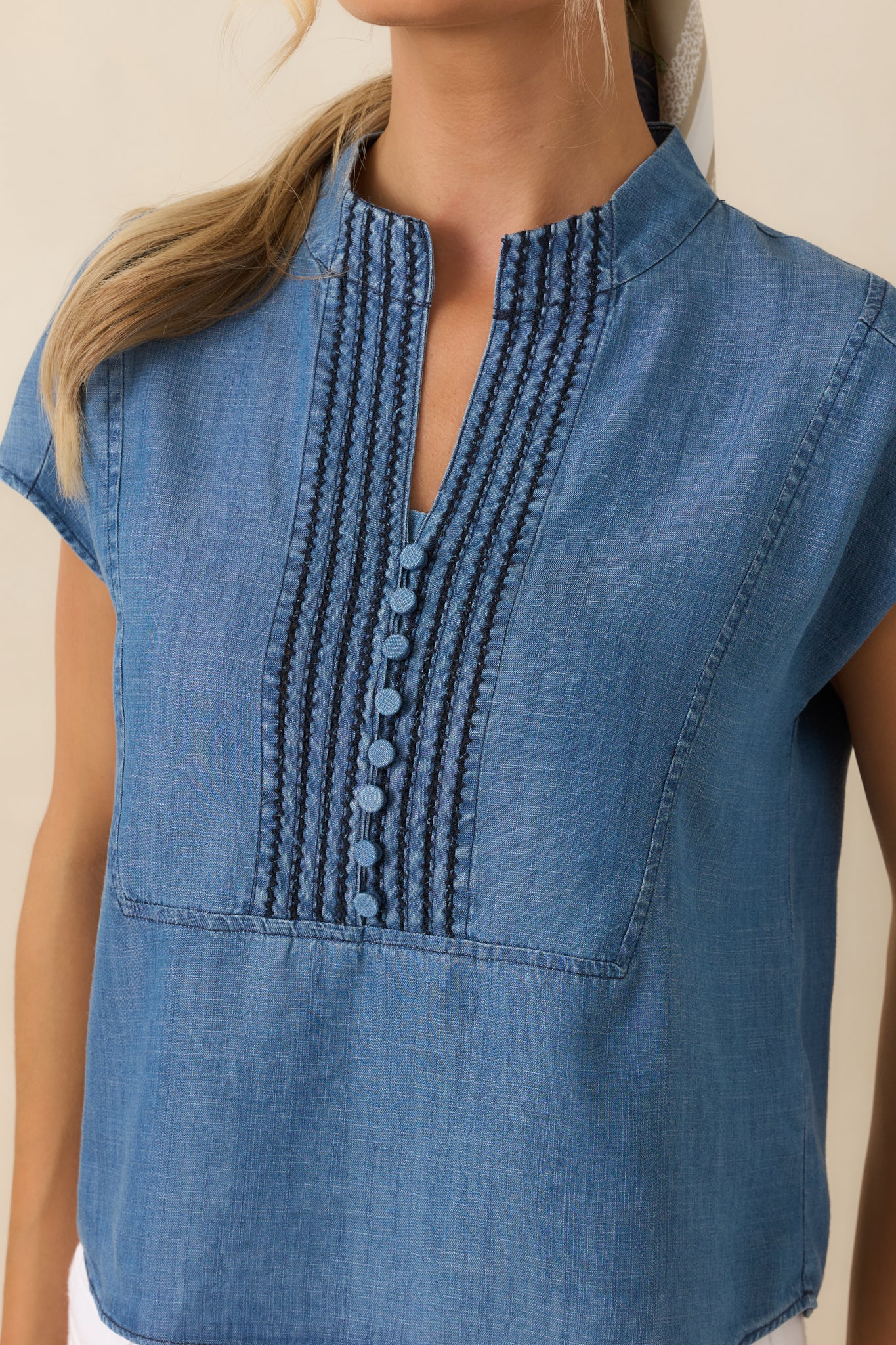 Close-up of the blue top highlighting embroidered pintuck detailing, decorative covered buttons, and lightweight lyocell fabric texture.