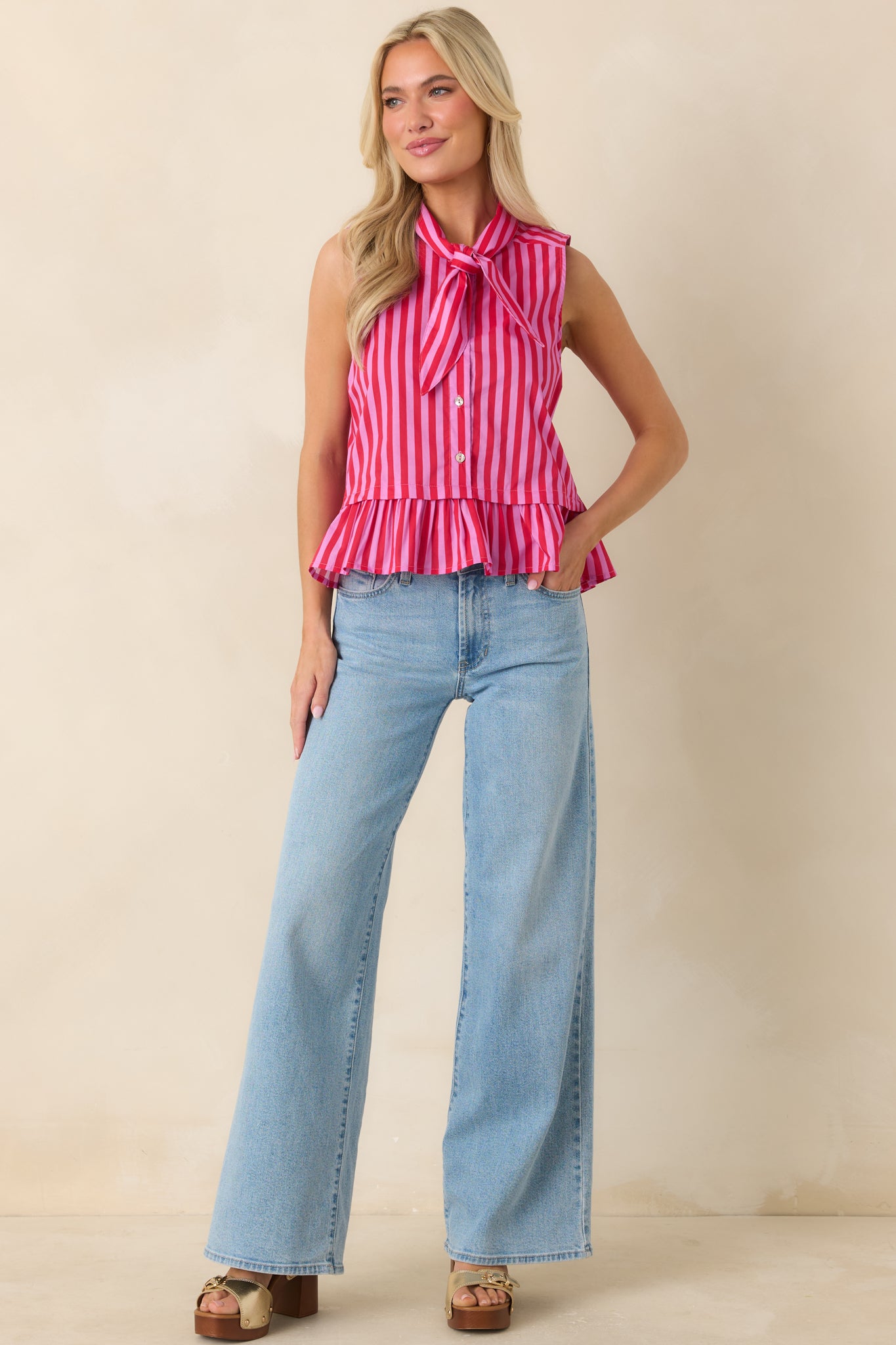 Sleeveless red and pink striped cotton top showcasing a relaxed fit with button front detailing and airy drape.

