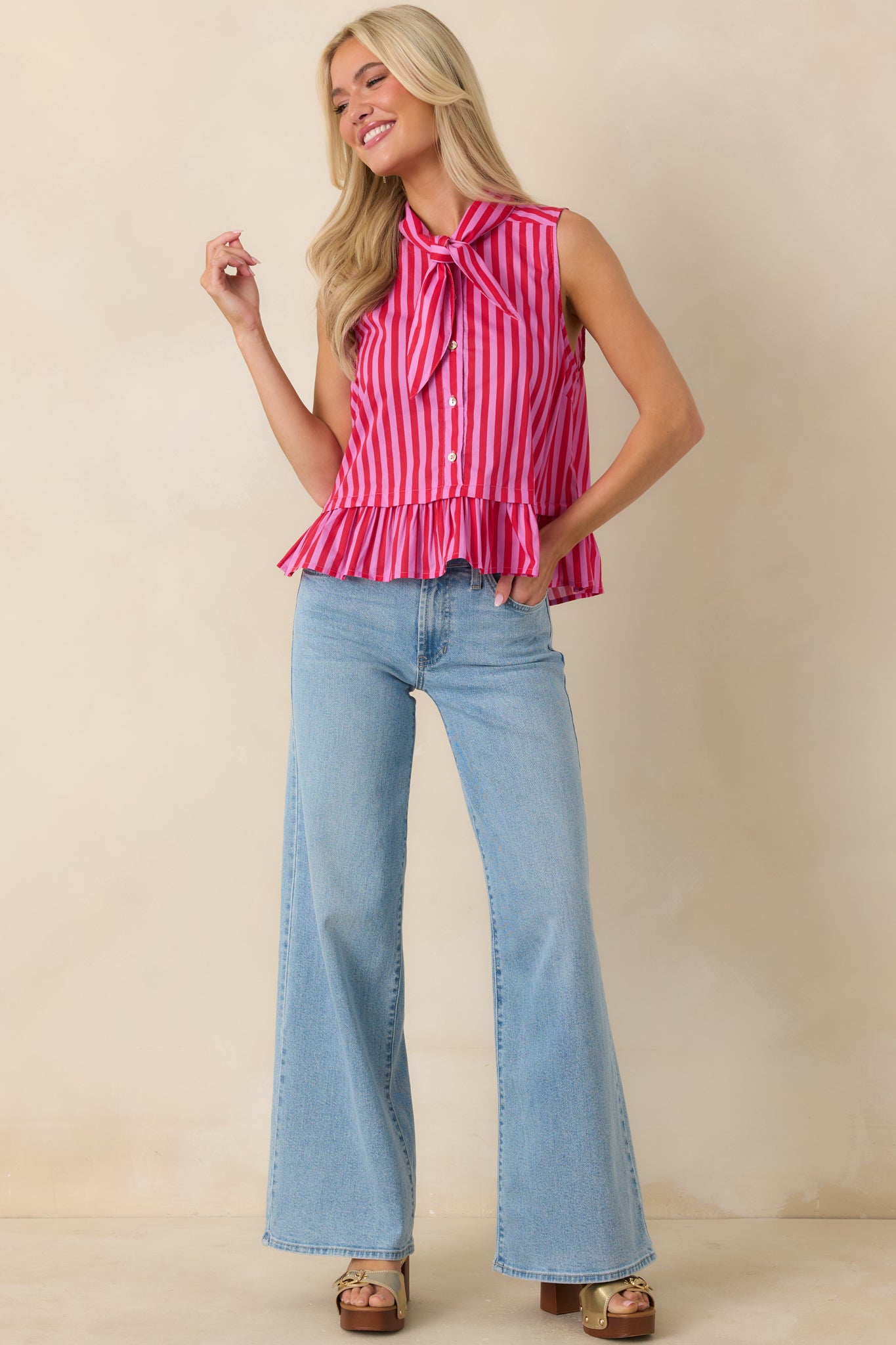 Red and pink striped top with ruffled hem, sleeveless silhouette, and soft 100% cotton construction.