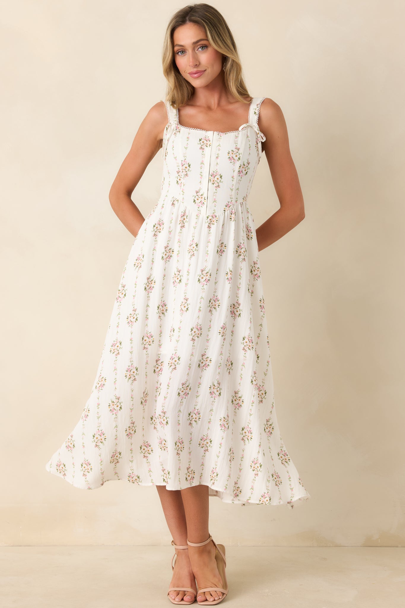 White floral midi dress featuring a fitted bodice with front hook and eye closures, delicate trim accents, and a graceful midi length.