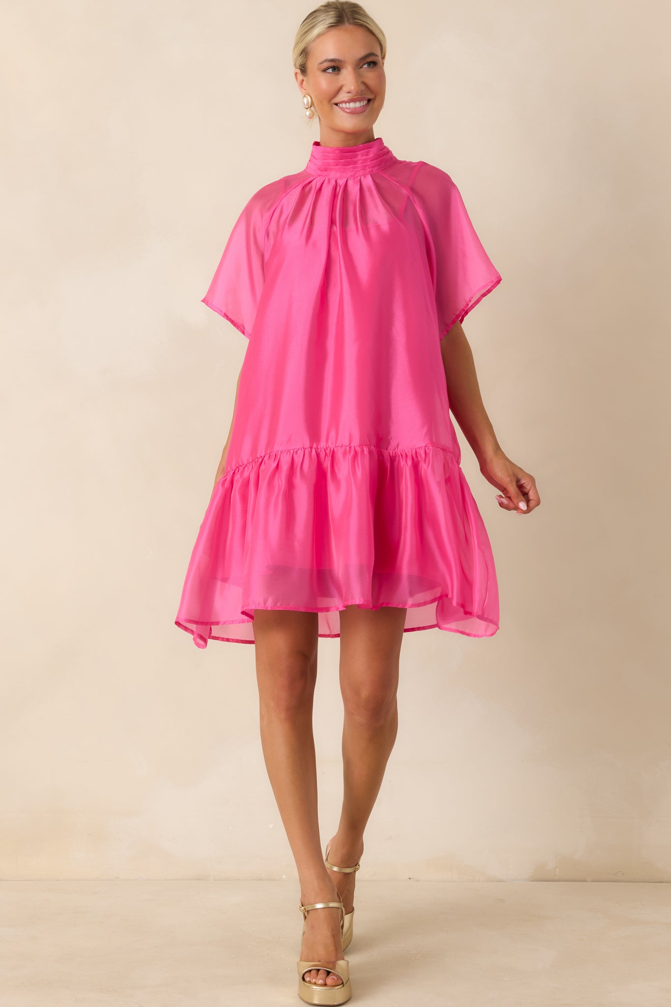 Pink organza mini dress featuring a high mock neckline, sheer flutter sleeves, and a relaxed shift silhouette.