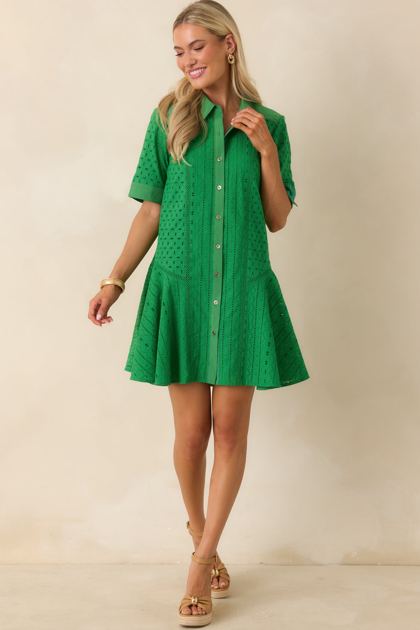 Green mini dress with allover eyelet fabric, a structured collar, and a softly flared skirt shape.