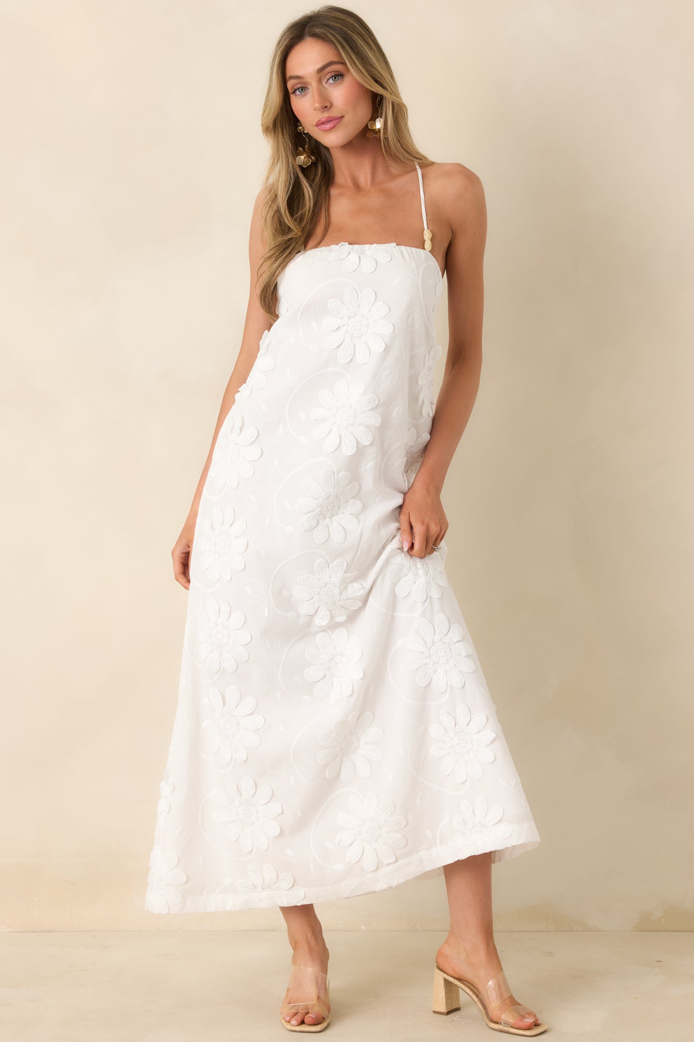 Front view of a white cotton maxi dress with tonal floral appliqué, clean front, and flowing silhouette.