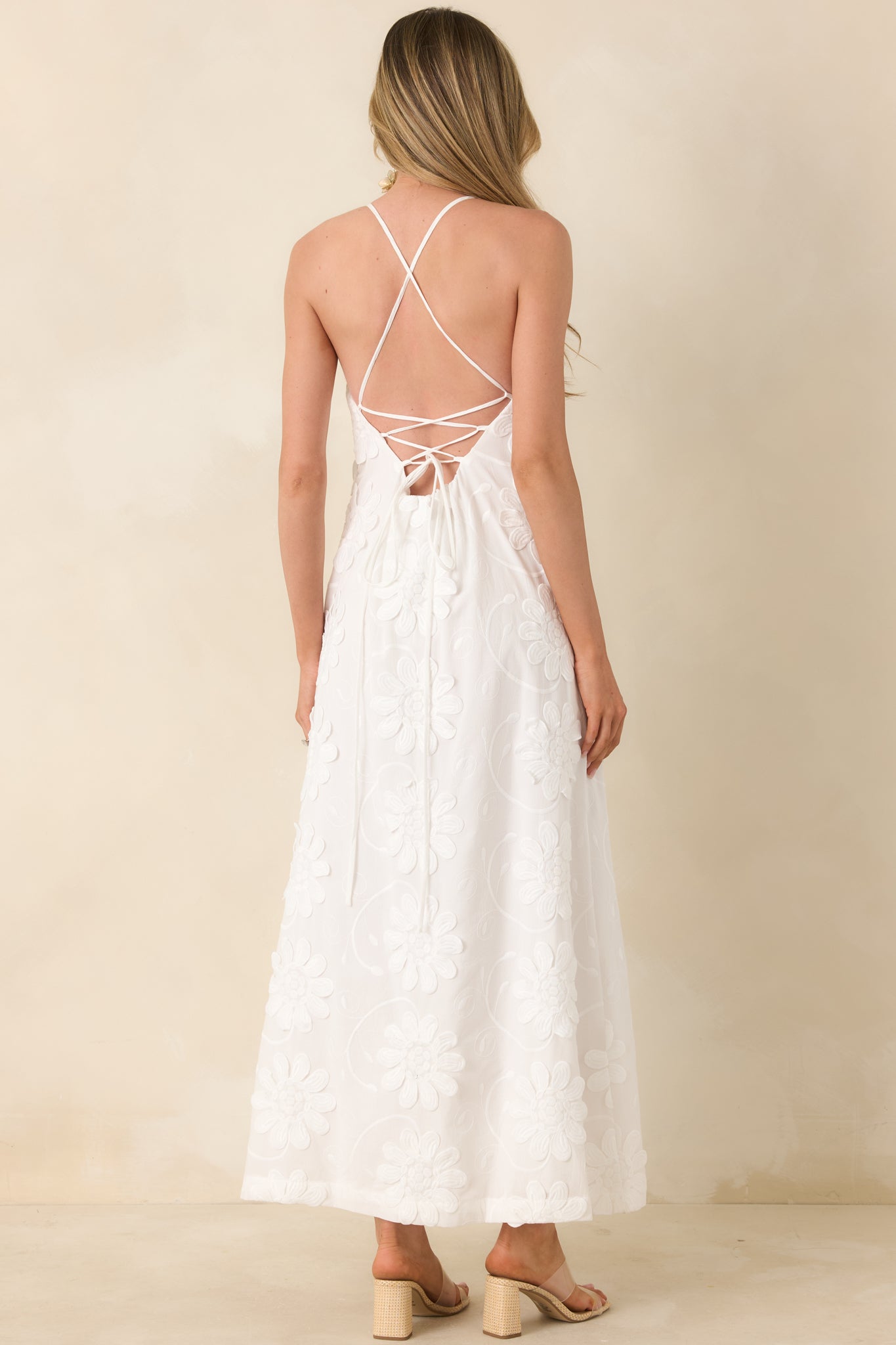 Back view of maxi dress featuring open lace-up back with slender crisscross straps and flowing skirt.