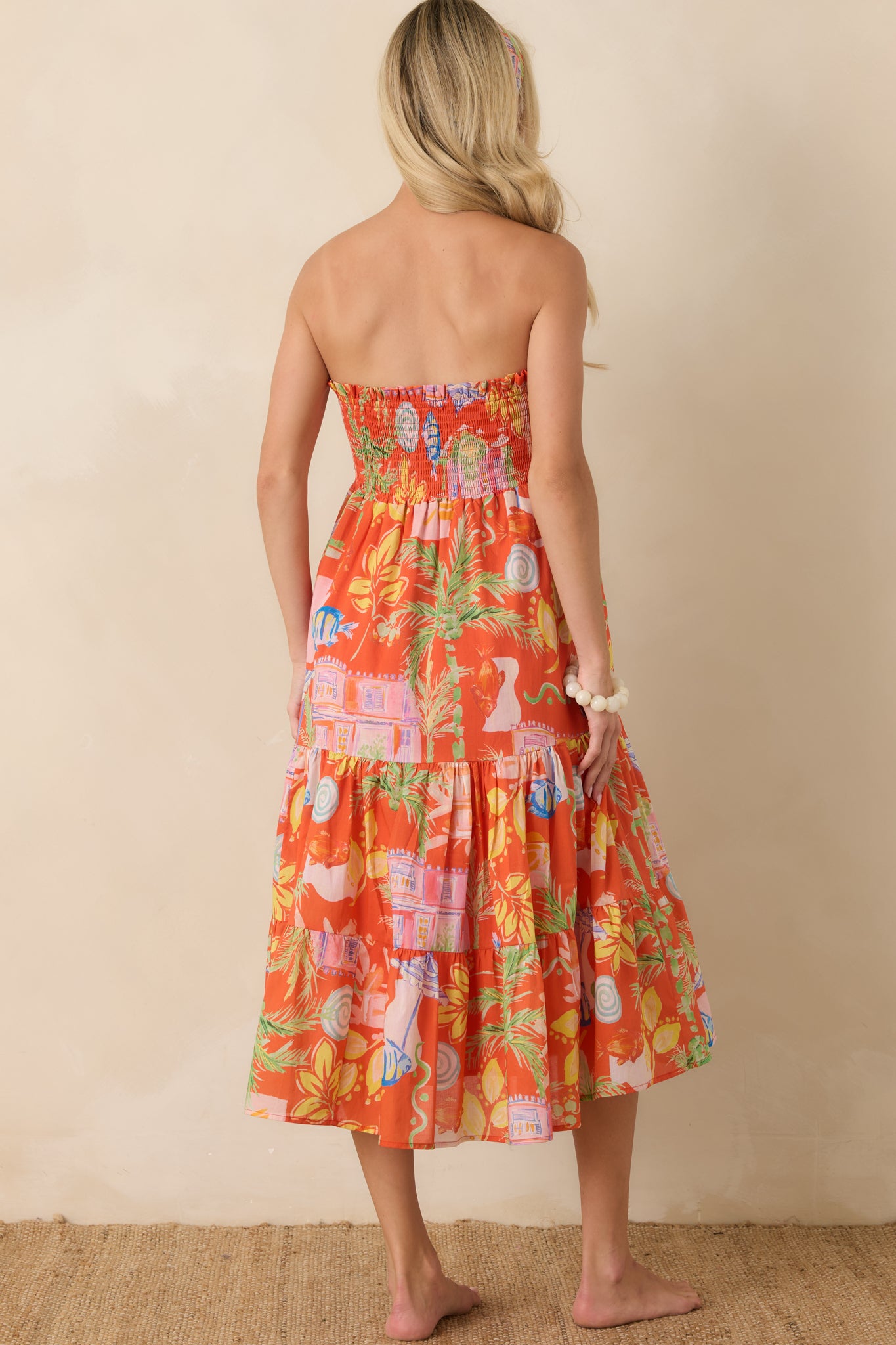 Rear view of the orange multi convertible dress featuring a smocked stretch bodice and flowing tiered skirt silhouette.