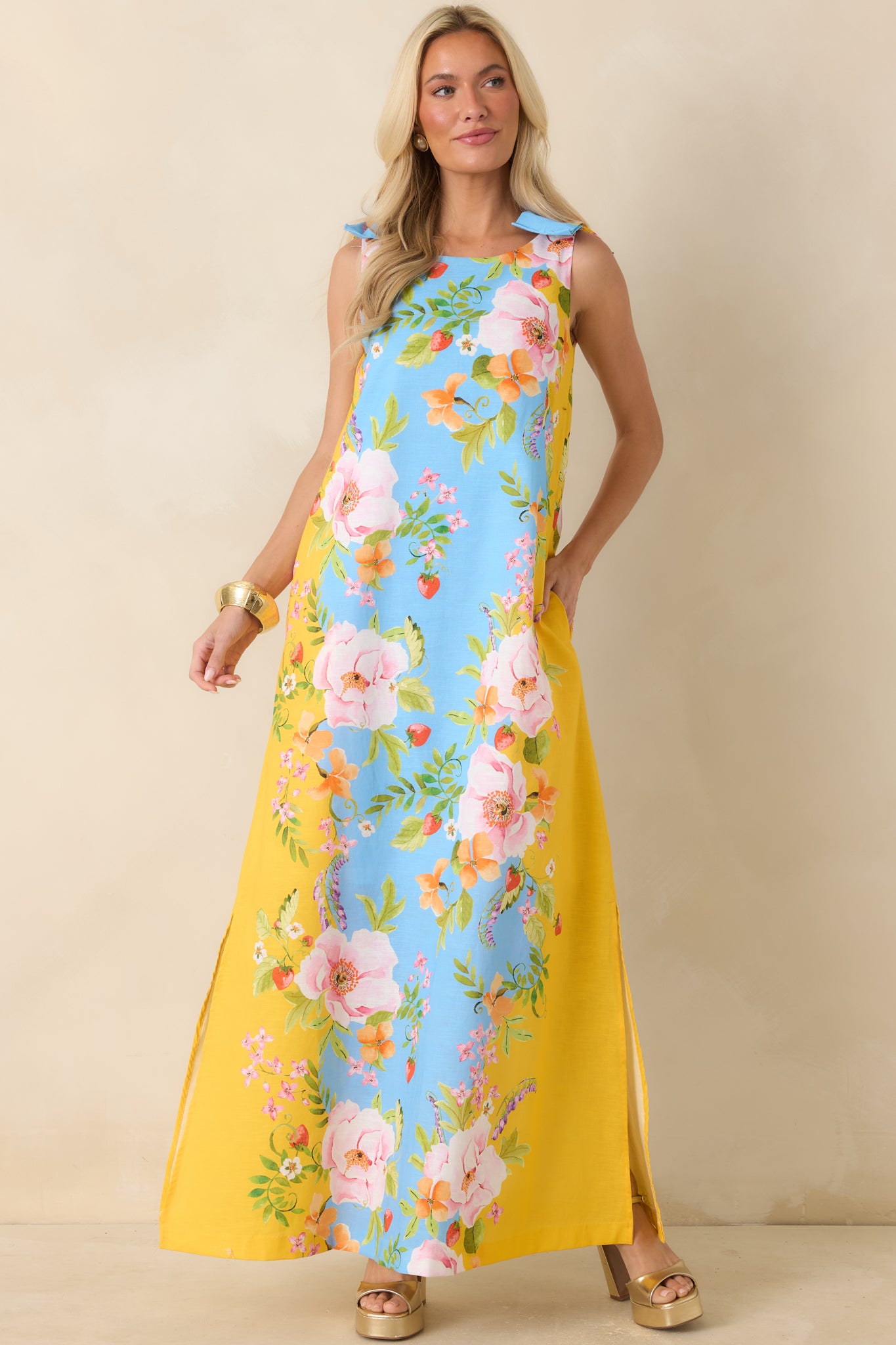 Blue and yellow floral maxi dress featuring a round neckline, bow-tie shoulder straps, and a relaxed flowing silhouette.