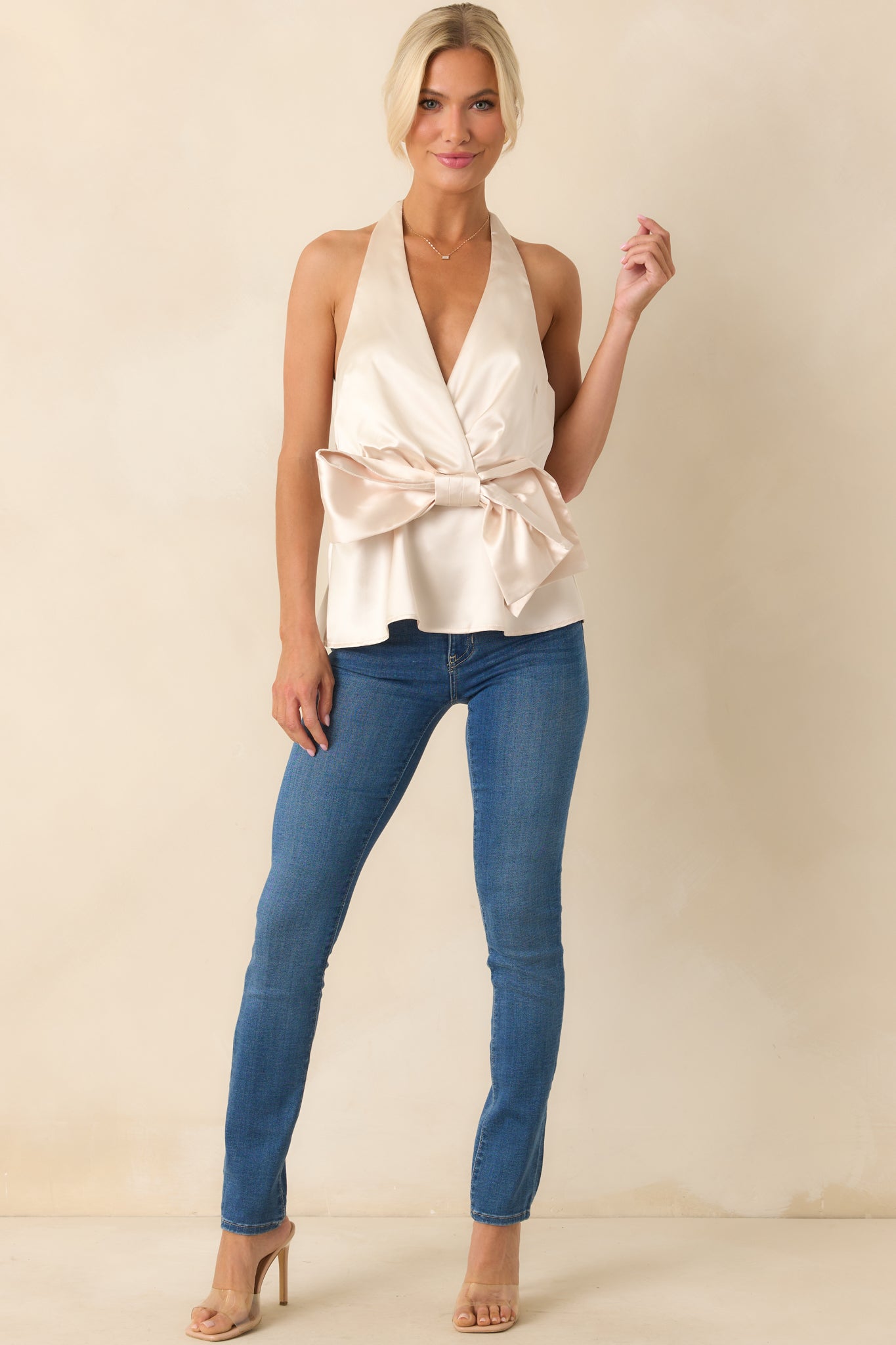 Full body view of the ivory halter top featuring a dramatic front bow and flared peplum accent.

