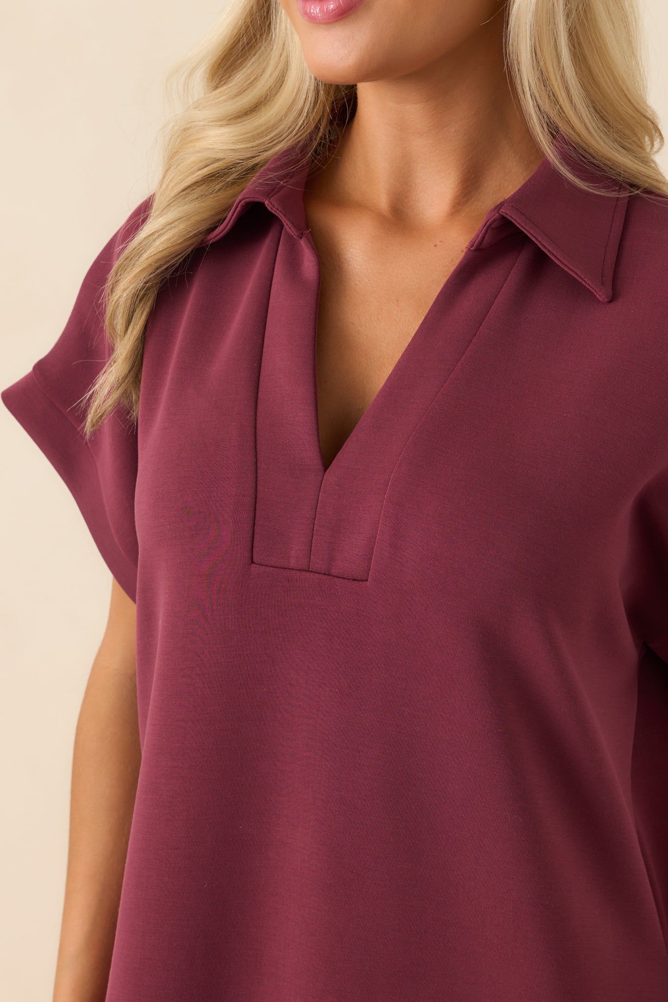 Close-up of buttery soft burgundy fabric with notch v-neckline and collar seam detail.