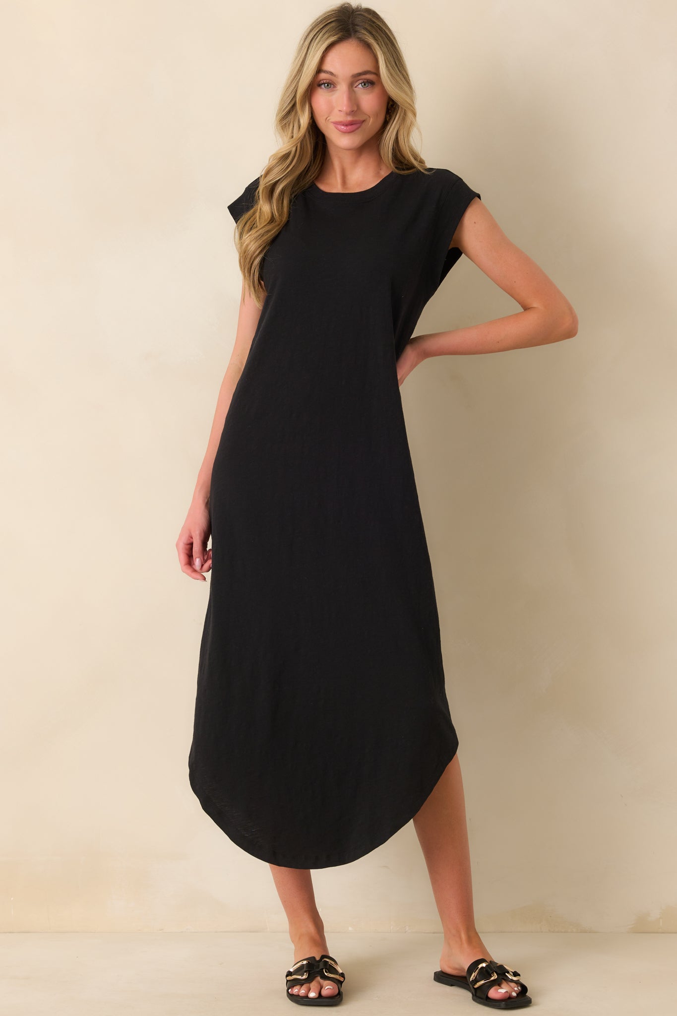 Full length black midi dress emphasizing relaxed fit and elegant scoop bottom hem.