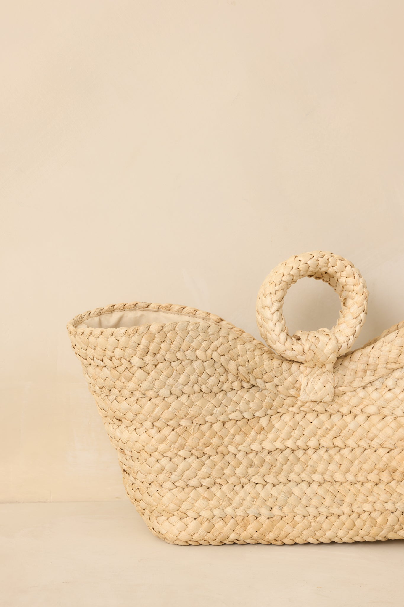 Side angle close-up of the tote emphasizing the depth of the open structure and raffia weave pattern.