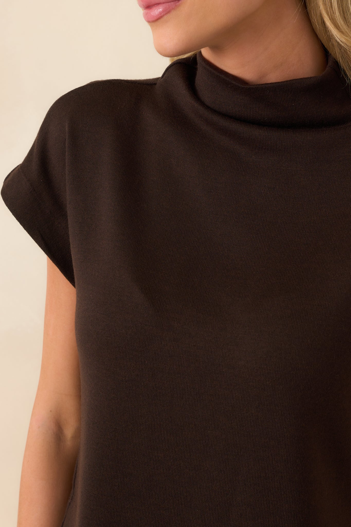 Close-up of the neckline and upper chest area showing the soft roll of the mock neck and fabric texture.