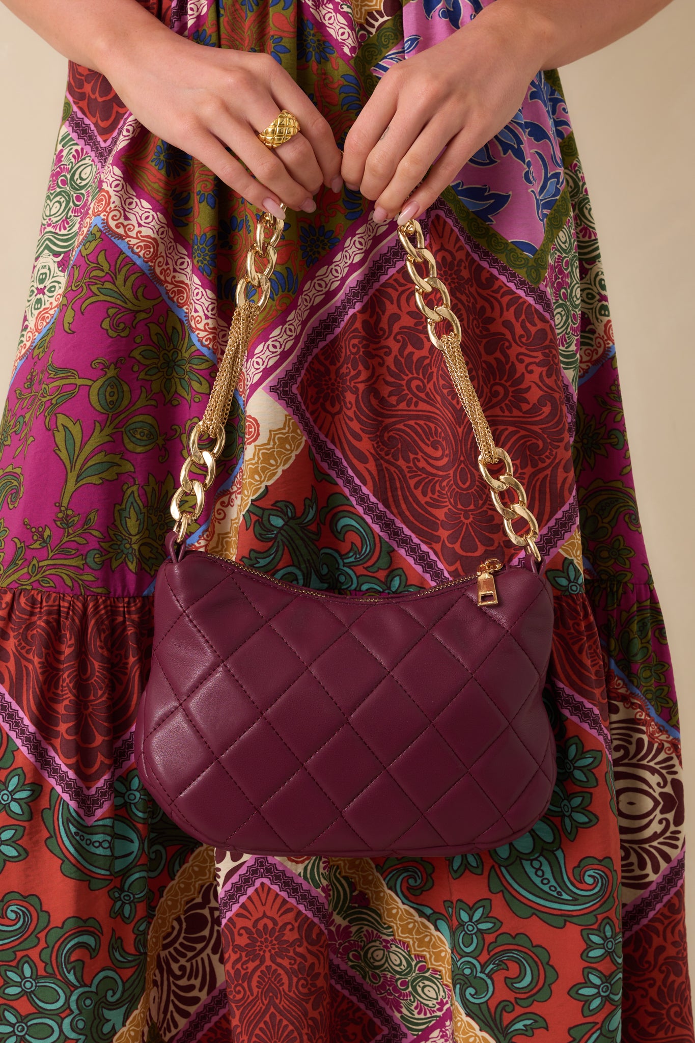 Front view of merlot quilted handbag featuring a gold zipper closure and optional thin gold chain shoulder strap.