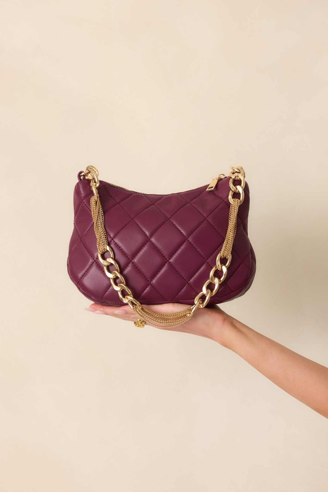 Close-up of the thick gold chain handle and quilted texture on the merlot handbag.