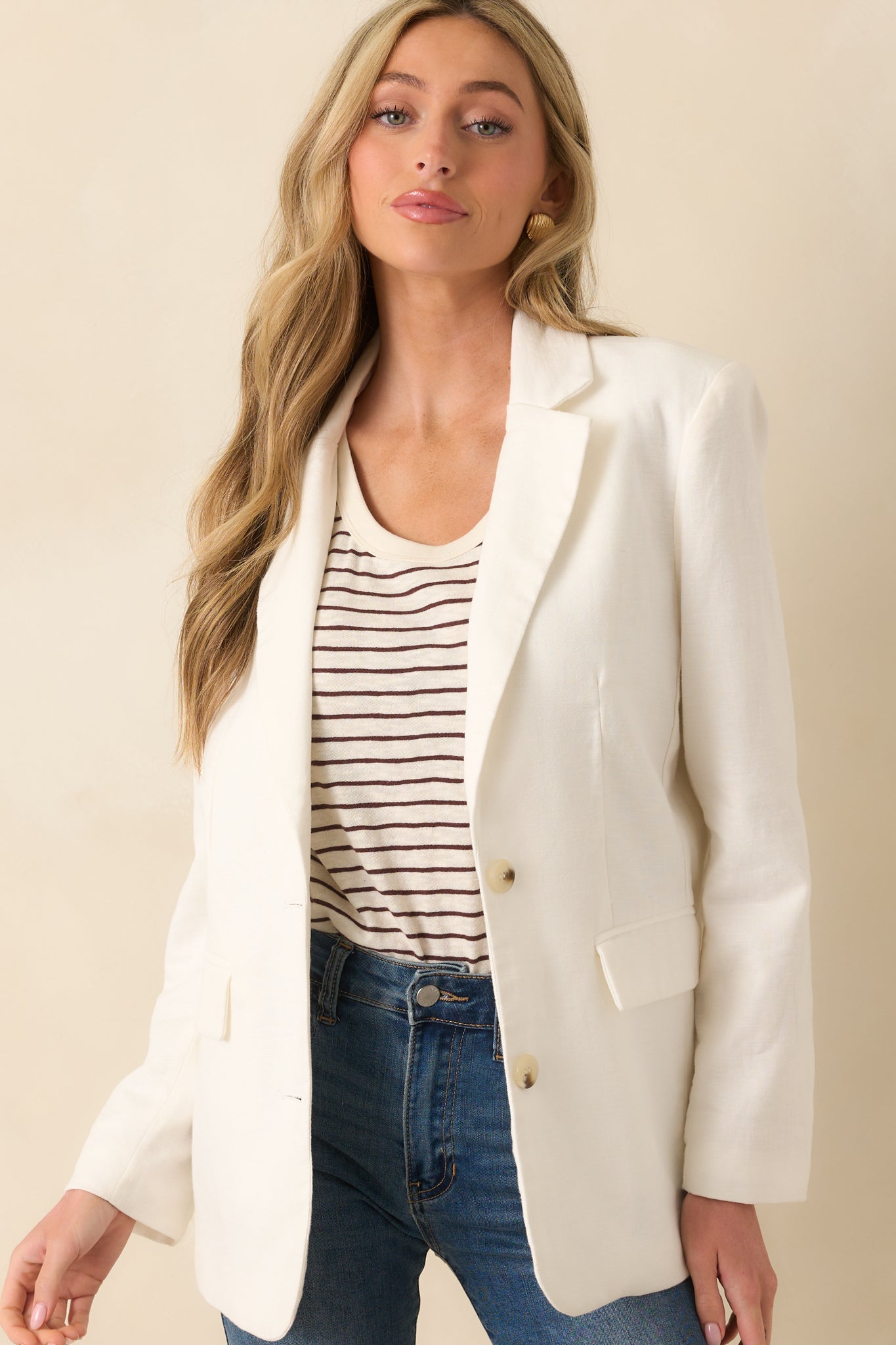 A cropped front view highlighting the collared neckline and button front of the white blazer.