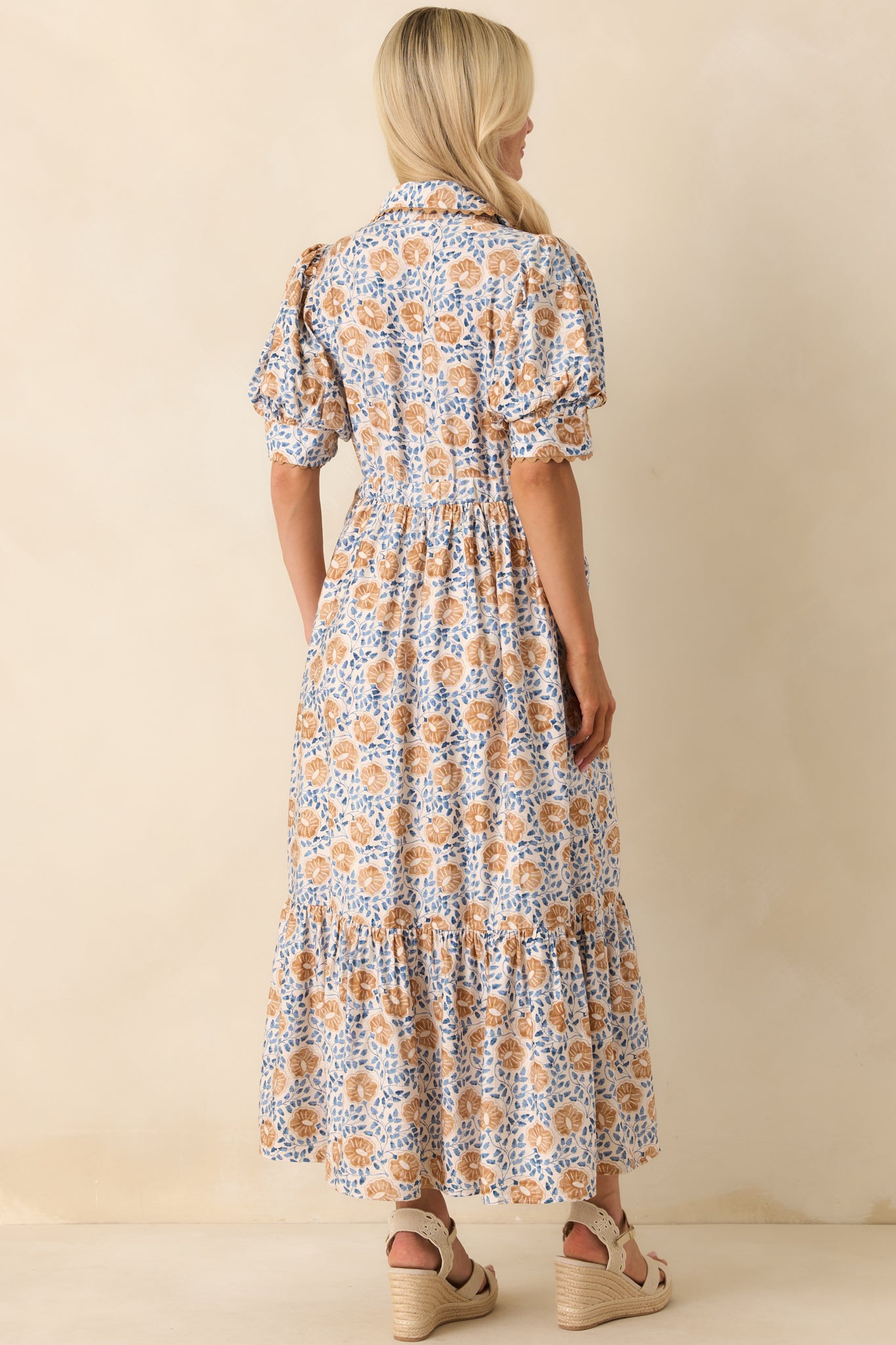 A view from behind showing the floral dress with adjustable waist ties on both sides and ric rac trim along the sleeve edges.