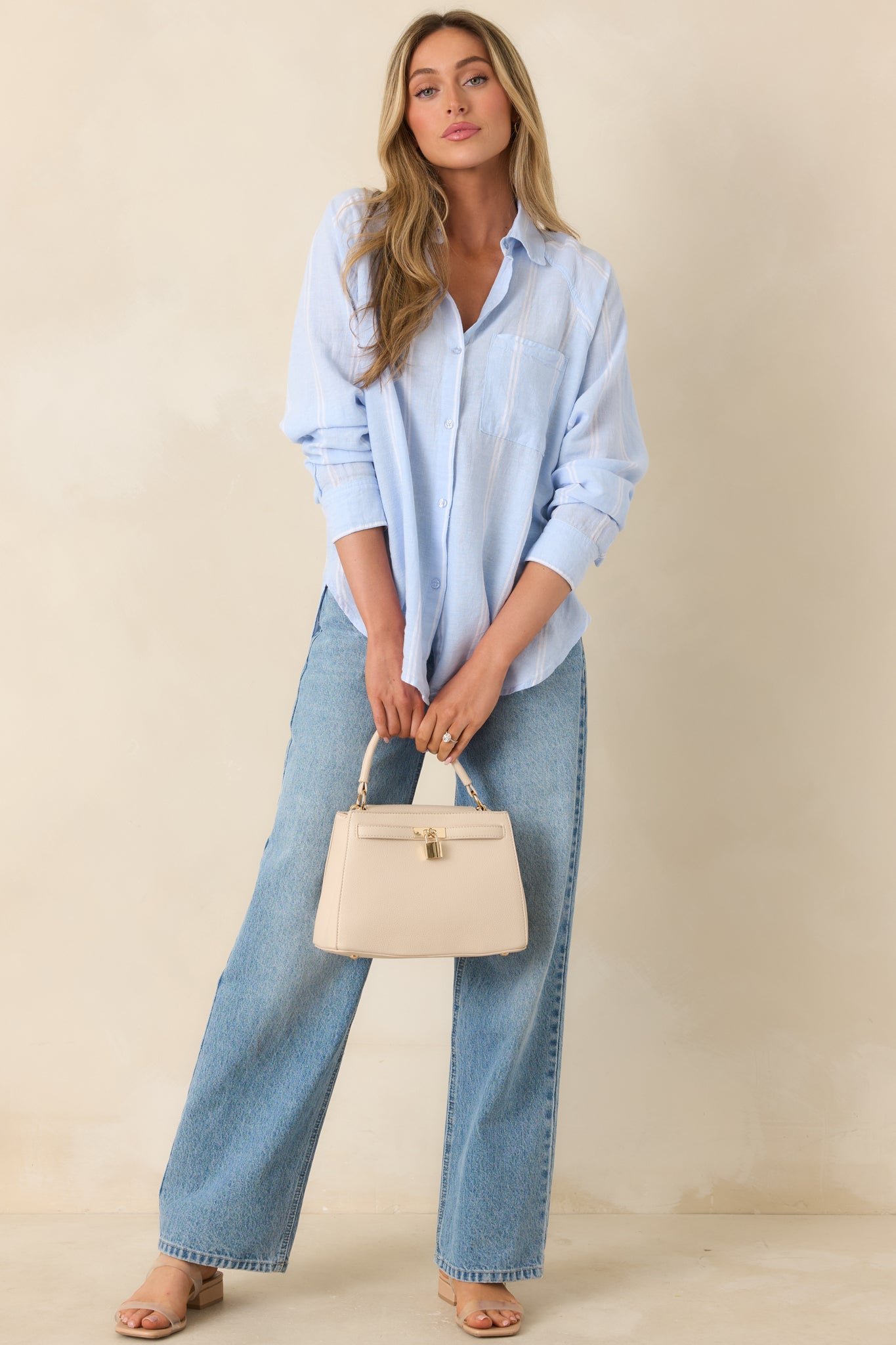 Soft blue and ivory striped button-up top with collared neckline and lightweight, flowy silhouette.