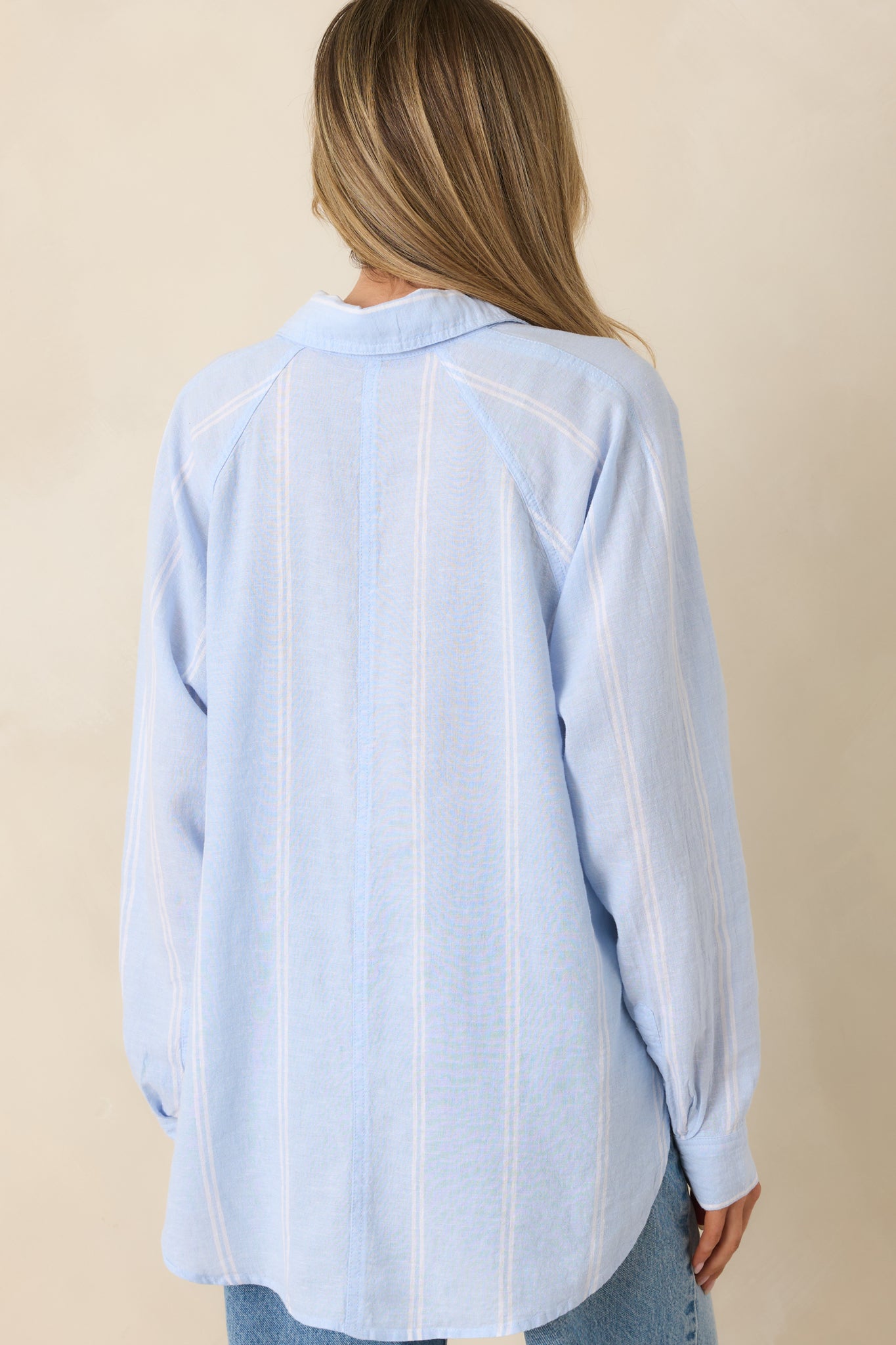 Rear view of lightweight linen blend top with soft blue and ivory vertical stripes and relaxed drape.
