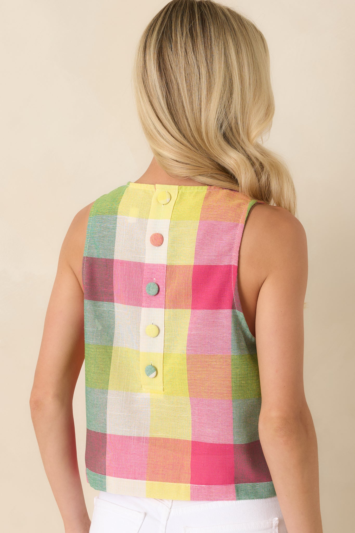 Back view of the sleeveless plaid top highlighting the button-back closure design and smooth, slightly cropped silhouette.