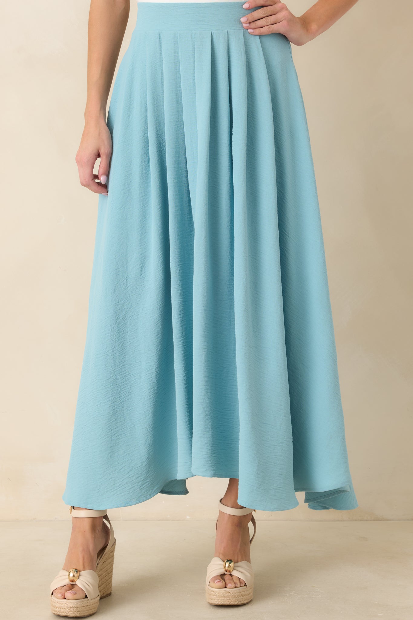 Cropped detail of the turquoise skirt featuring the flowing silhouette and softly curved hemline.