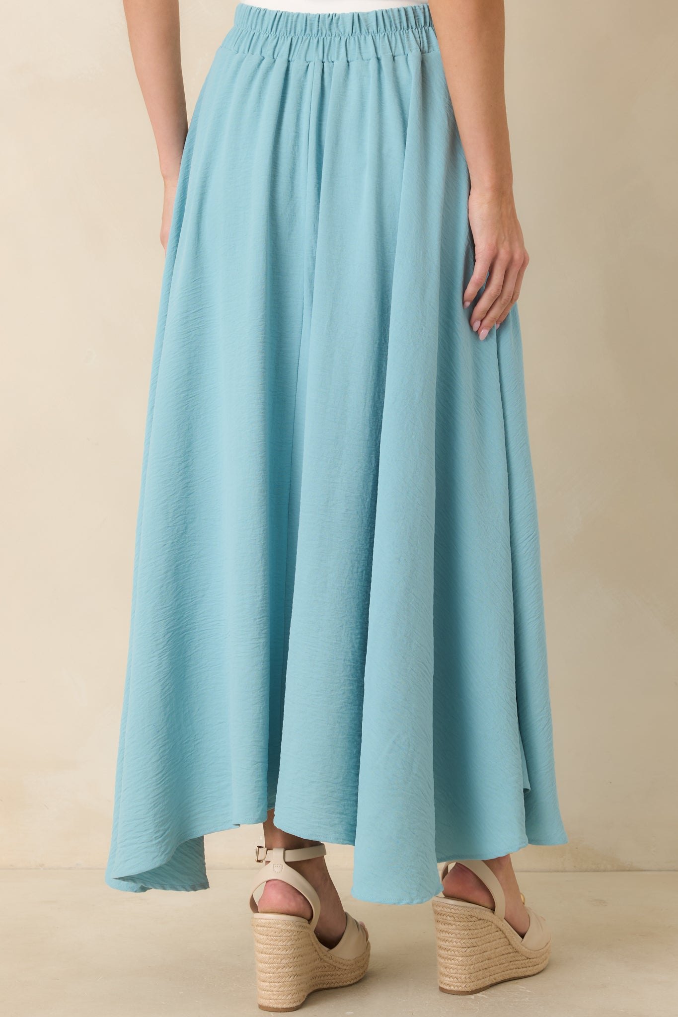 Rear view of the turquoise maxi skirt featuring a flowy full-length silhouette, curved hemline, and comfortable elastic waistband.