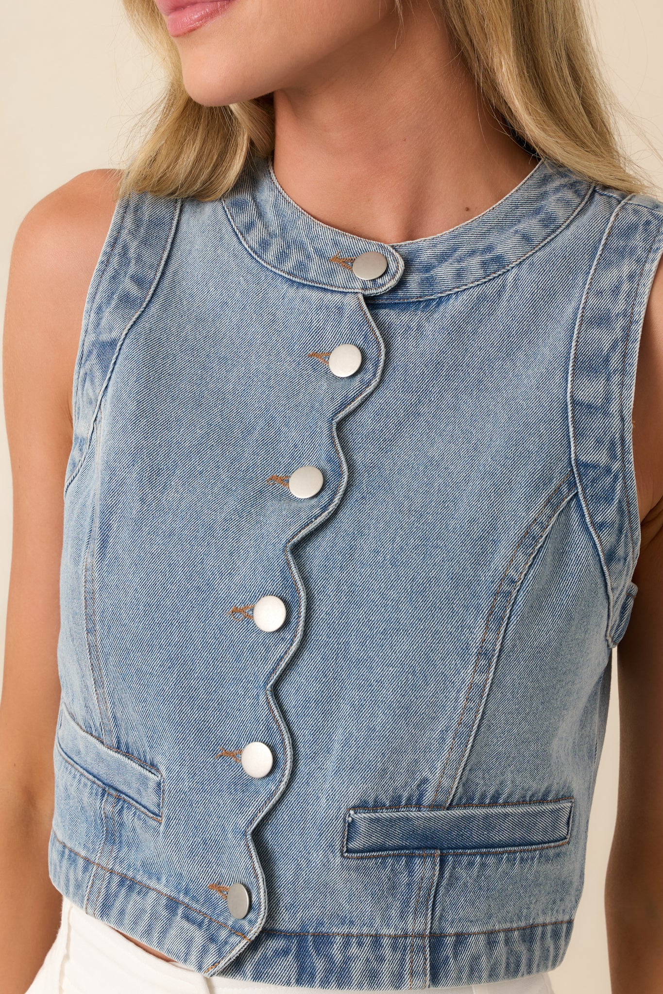 Close-up of medium wash denim showcasing welt pocket detail and precise stitching.