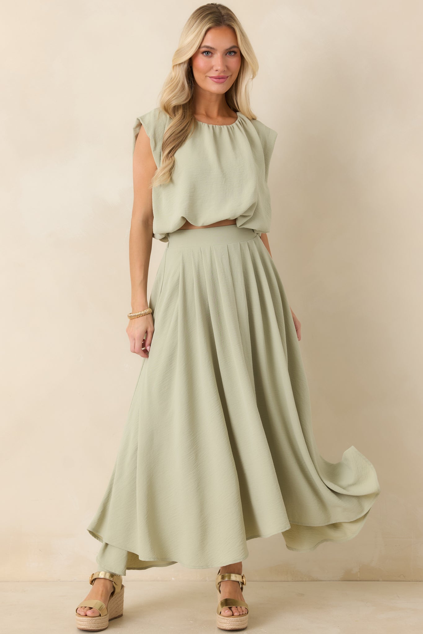 Sage green cropped top featuring elasticized hem, relaxed blouson fit, and a lightweight airy drape.