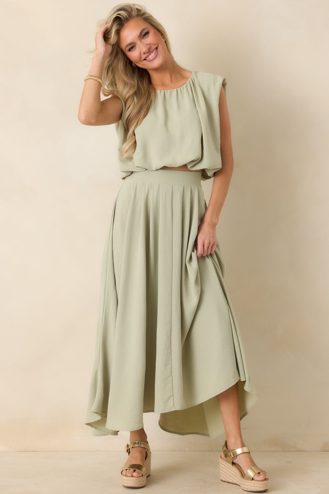 Sage green blouson cropped top with gathered neckline, sleeveless cut, and softly voluminous shape.