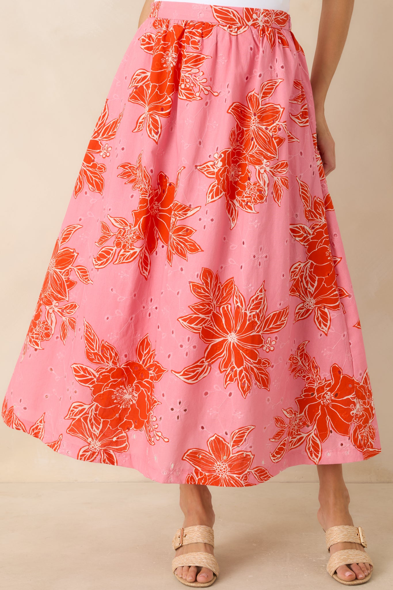 Cropped detail of pink and red floral print on lightweight cotton eyelet fabric.