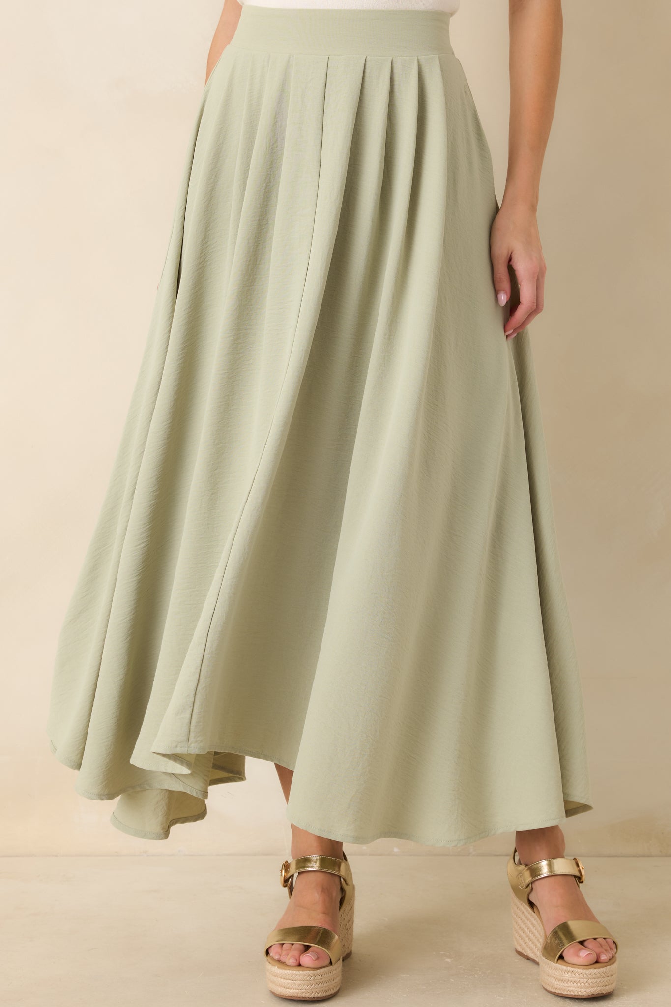 Elastic waistband detail on sage green maxi skirt with soft gathered fabric.