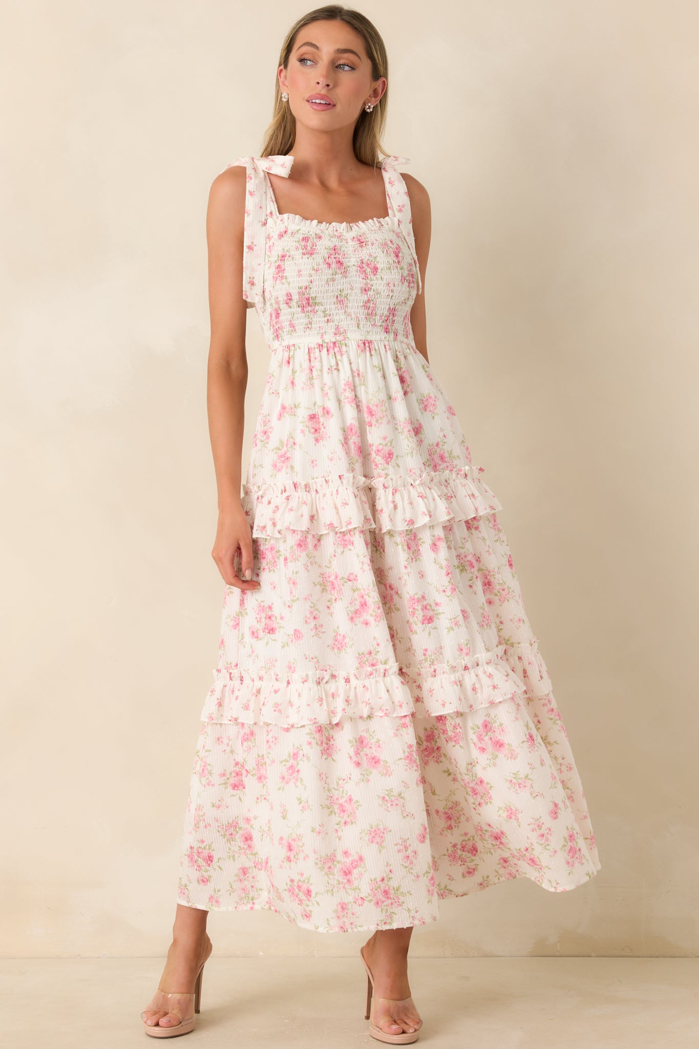 Lightweight floral dress featuring a delicate Swiss dot texture, smocked bodice, flowing tiered silhouette, and feminine tie shoulder straps.