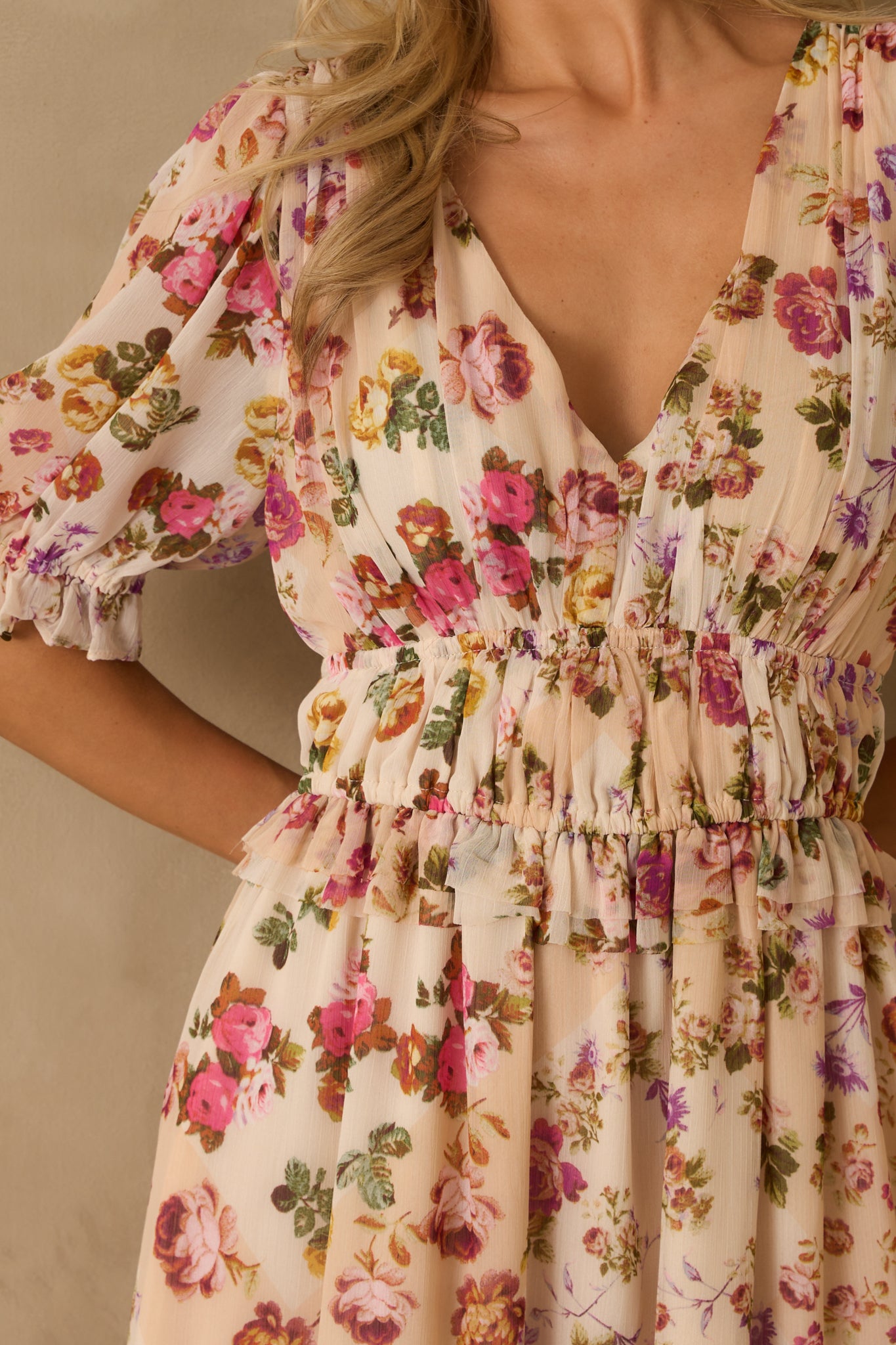 Close-up of beige fabric with pink floral pattern, highlighting ruffled trim and elastic waistband detail.