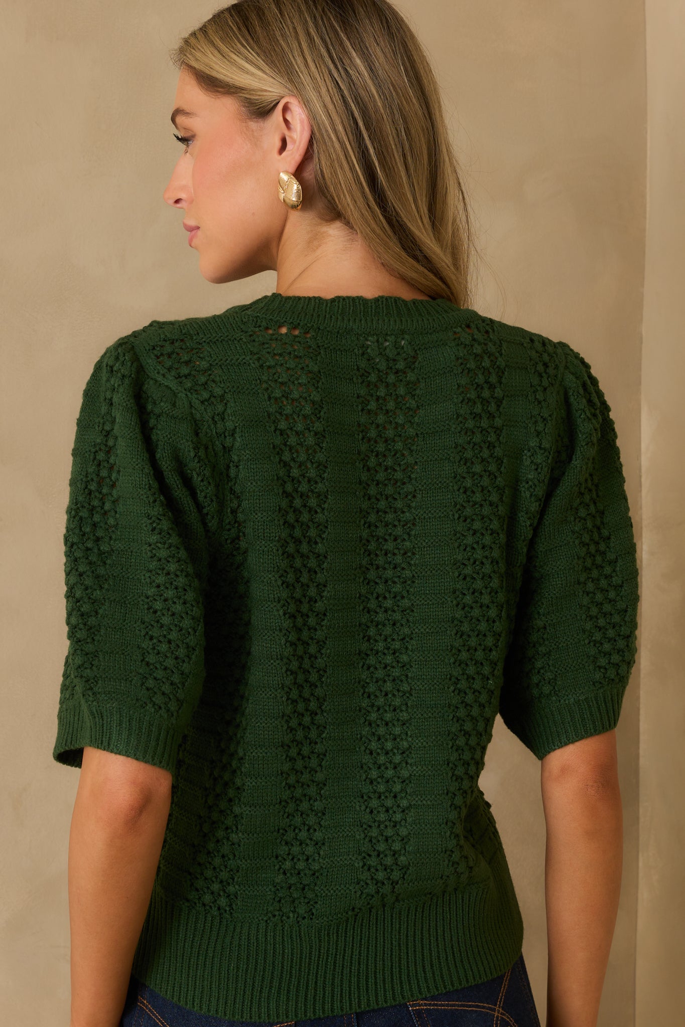 Rear view of the sweater showing the short sleeves, ribbed hem, and consistent vertical paneling across the back.