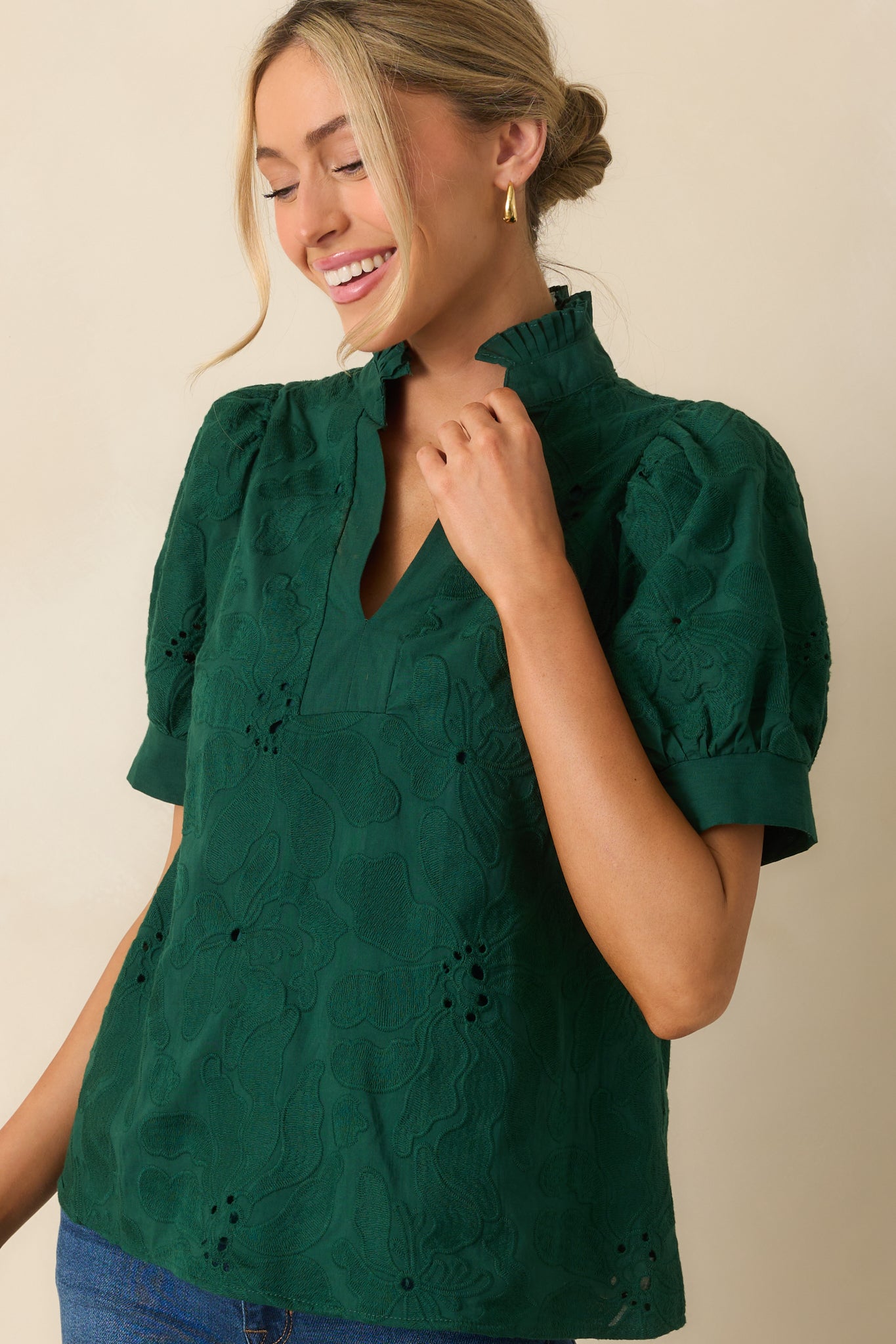 Detailed look at the textured floral embroidery and ruffle collar on the blouse.