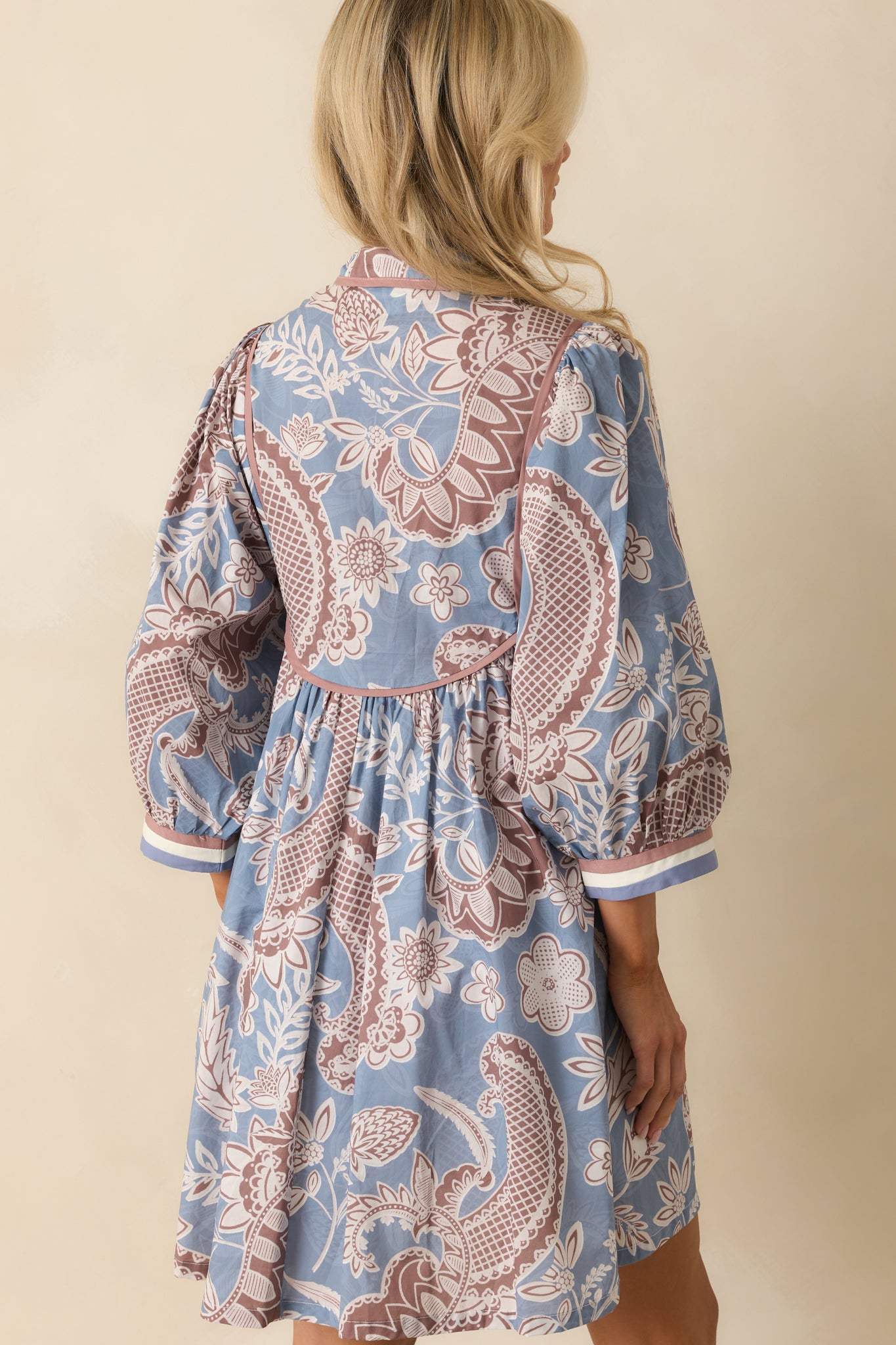 Rear view of the mini dress, showing the puff sleeves, flowing skirt, and full floral paisley pattern.