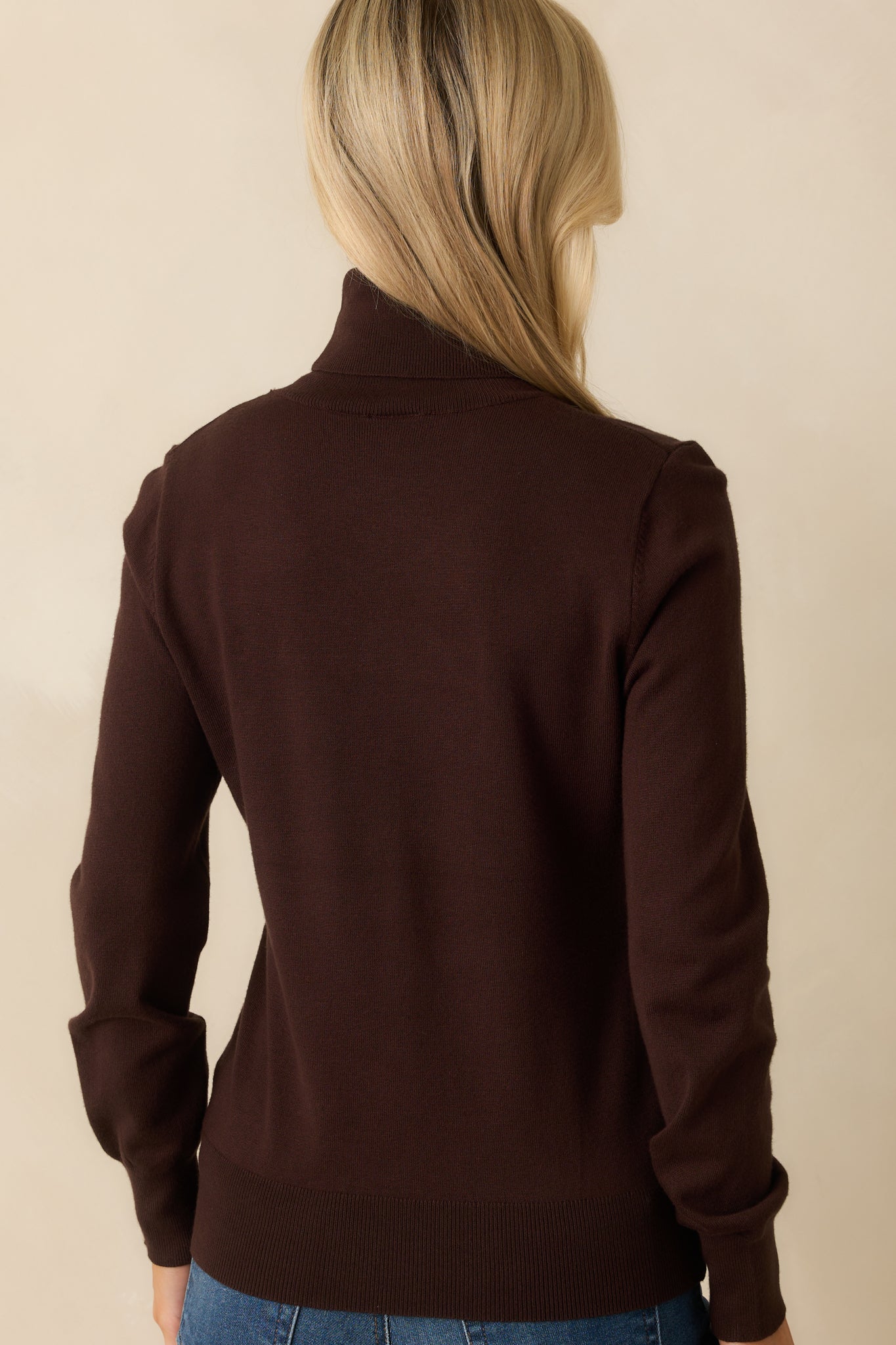 A back view of the sweater showing the smooth knit and ribbed bottom hem.