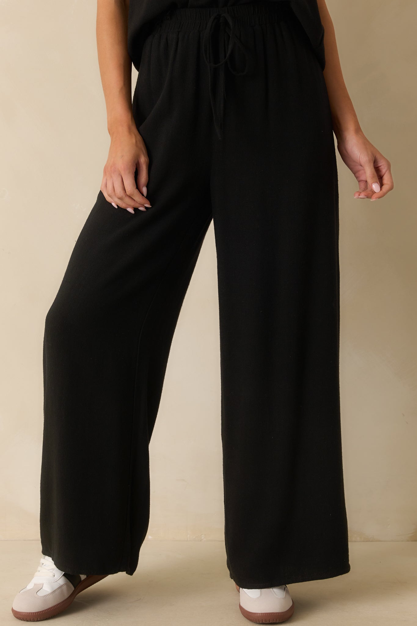 Cropped view focusing on the waistline and self-tie feature of the black pants.