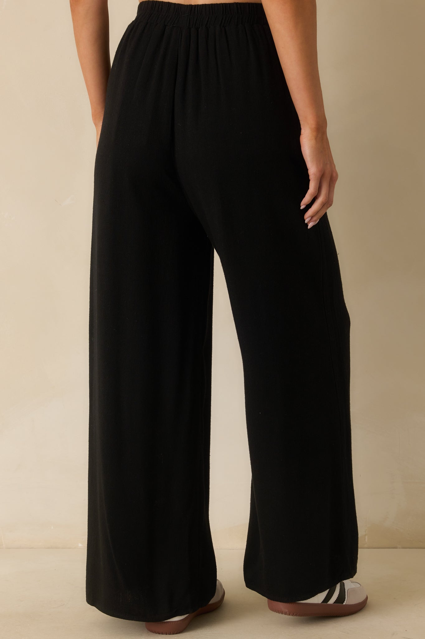 Back view of the black pants displaying the high waistline, relaxed fit, and wide leg design.