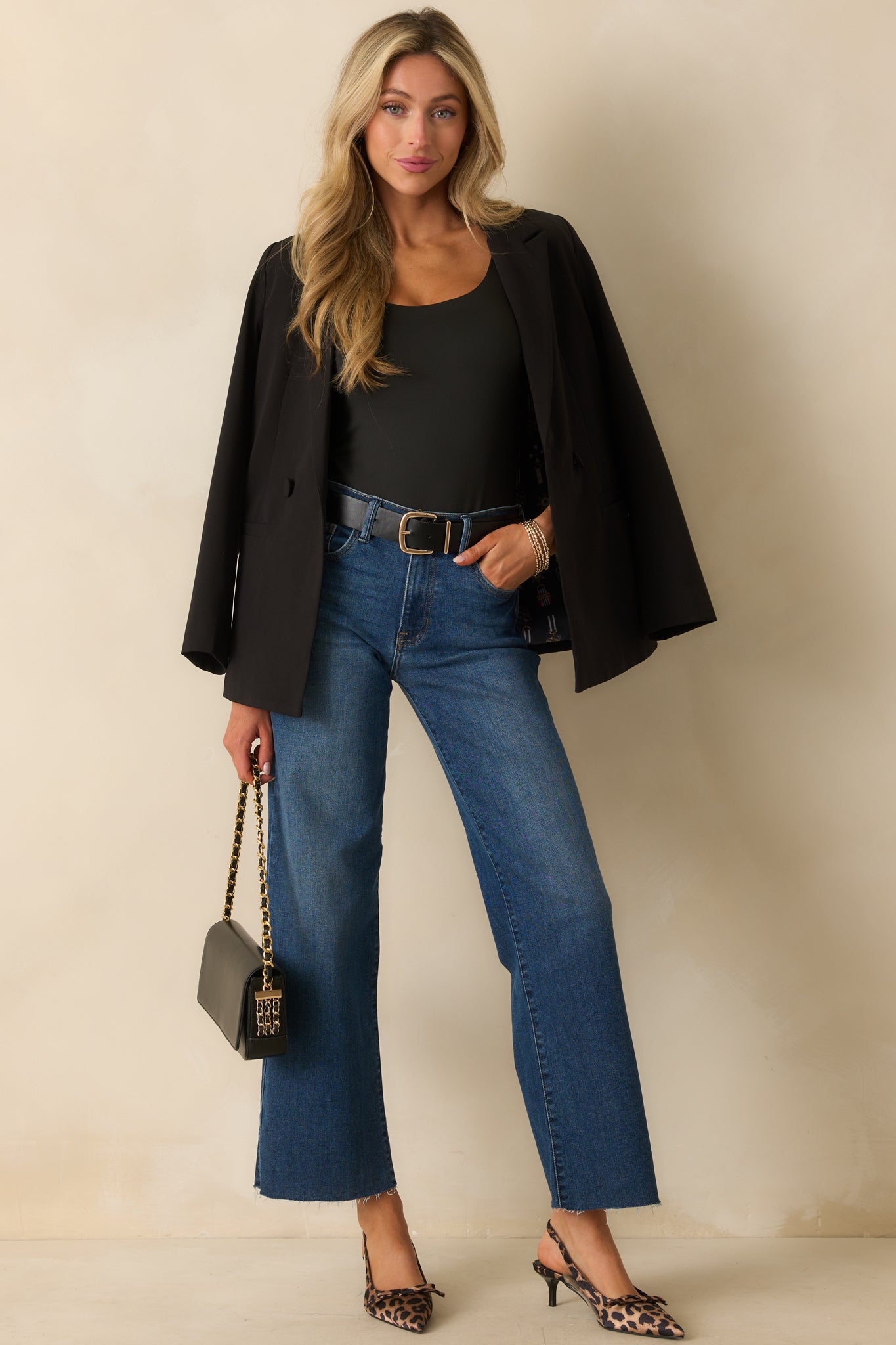 A full front view of the black blazer featuring a lapel collar and two functional front pockets.